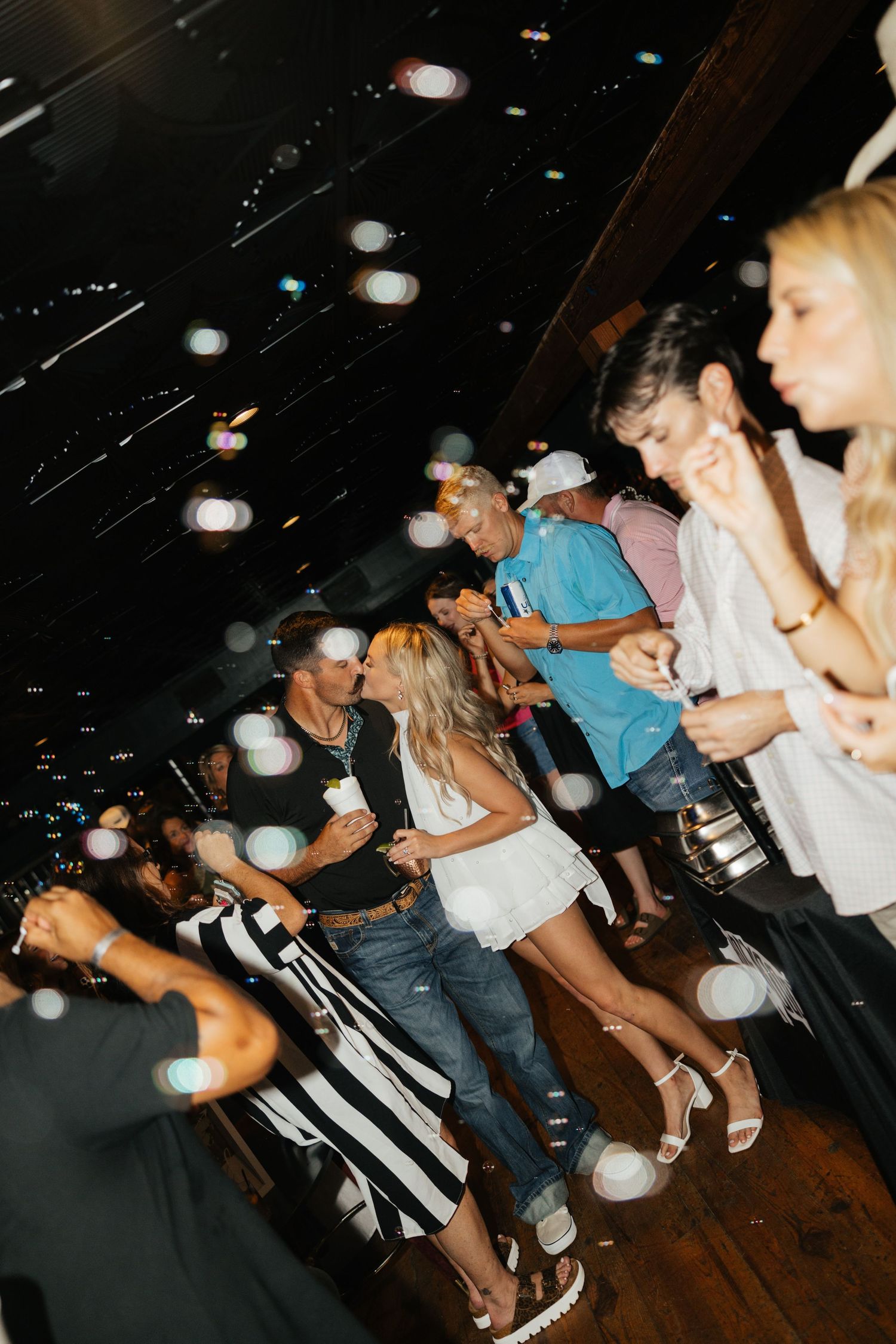 Guests dancing and celebrating on lively wedding reception dance floor with bokeh bubble effects.