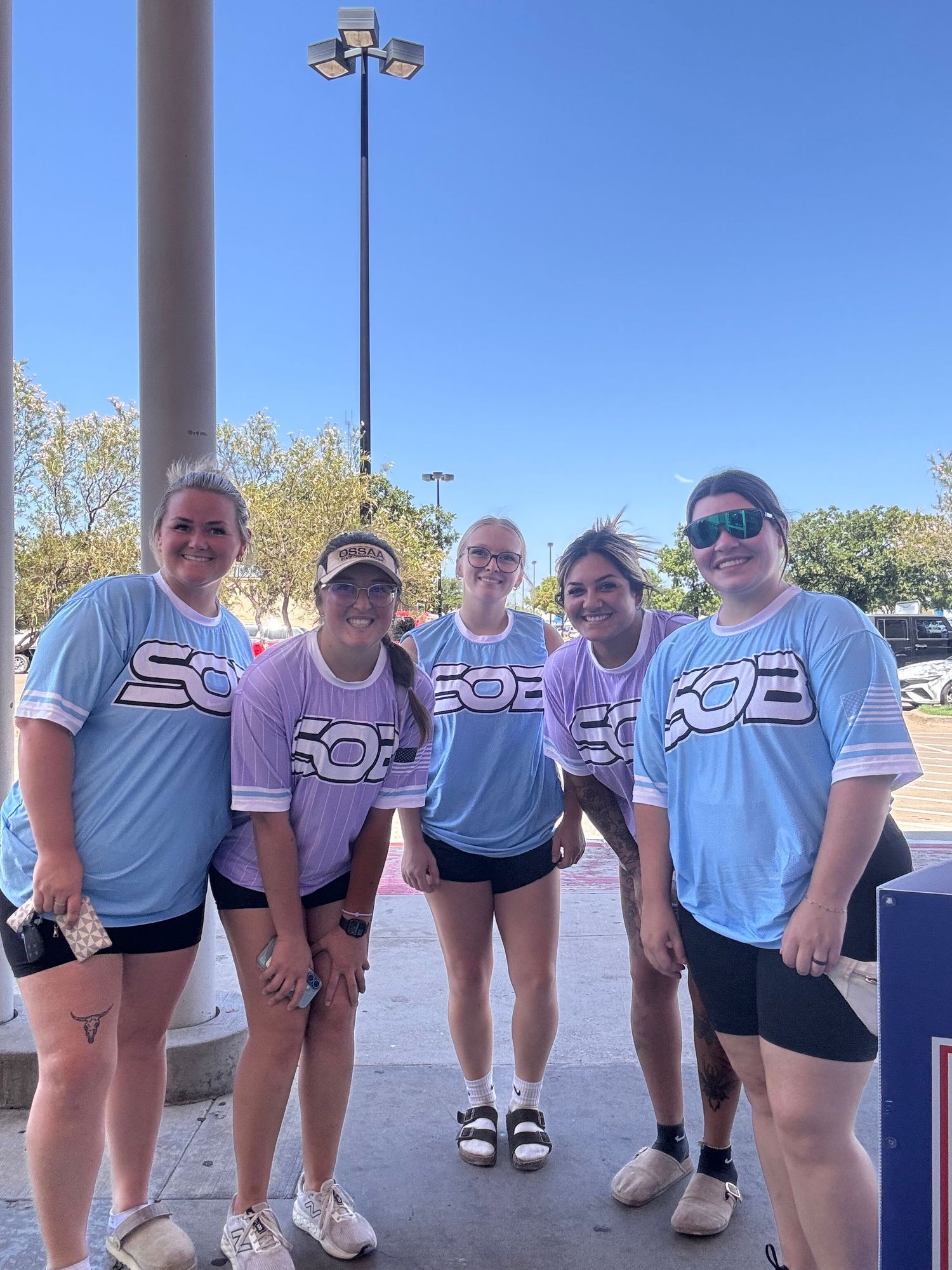 Five women in matching light blue SOB team jerseys posing outdoors on a sunny day.