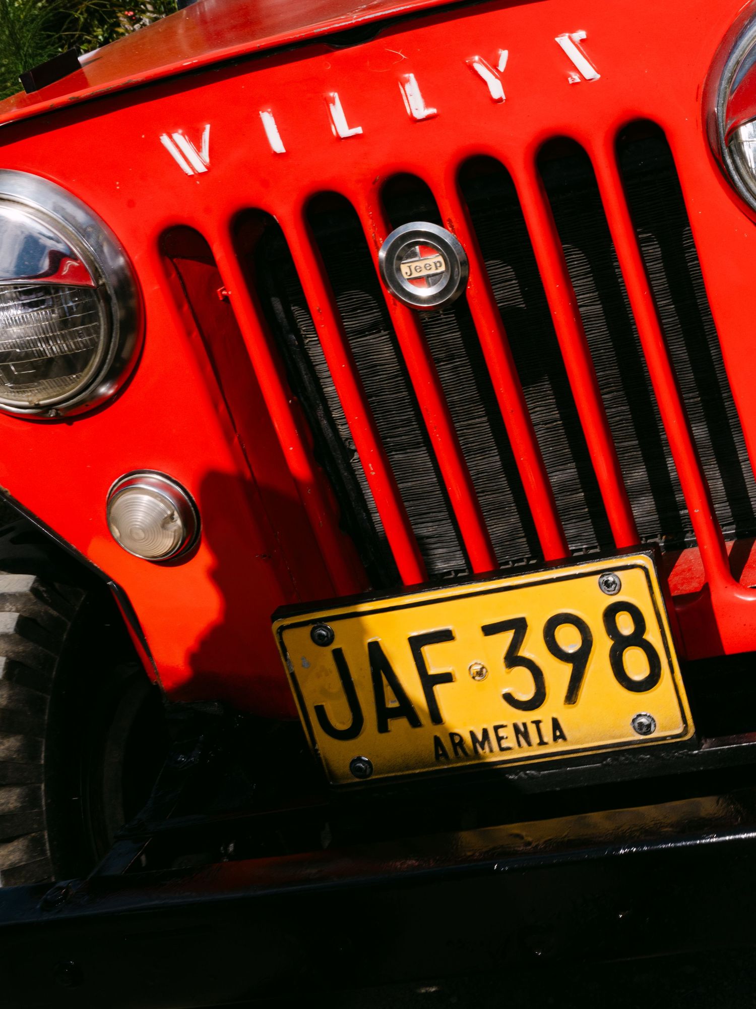 Close-up of a classic red Willys Jeep with Armenia license plate JAF-398 at a wedding venue.