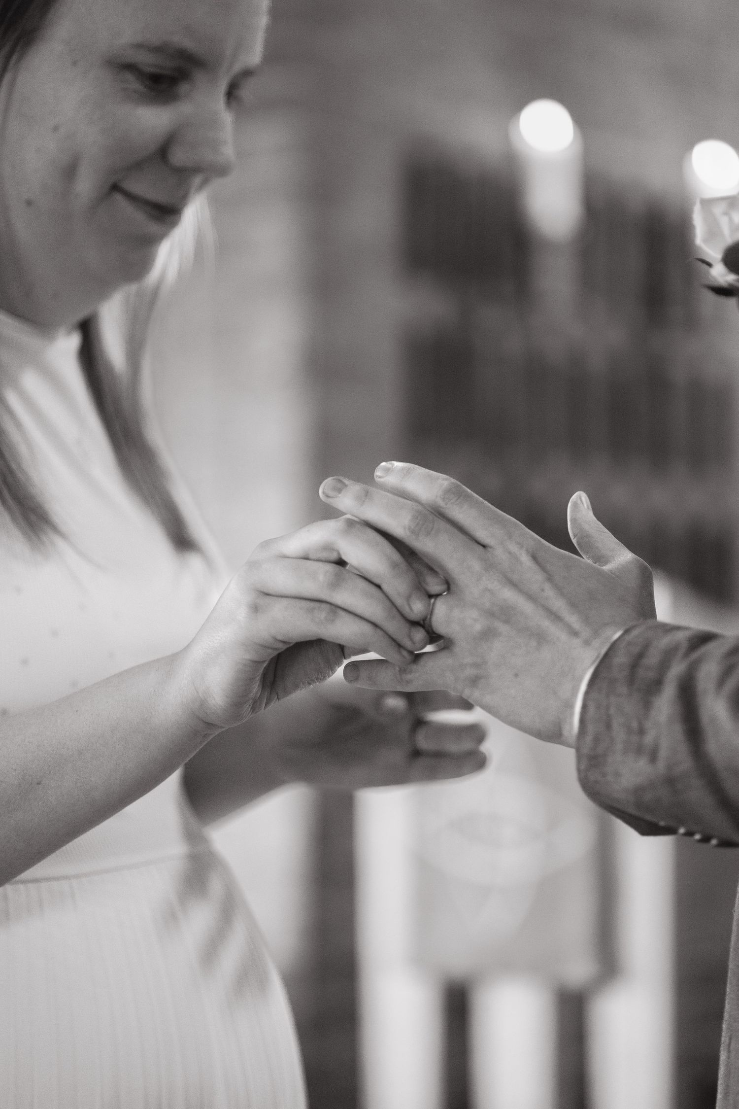 Black and white close-up of a bride and groom exchanging wedding rings during a ceremony.