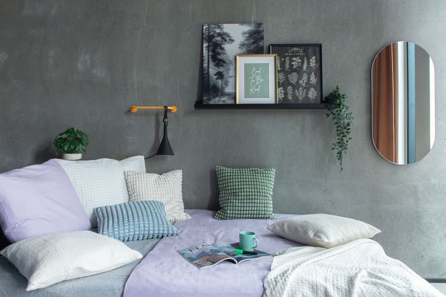 Cozy grey bedroom with lavender bedding, pillows, and wall shelf decor.