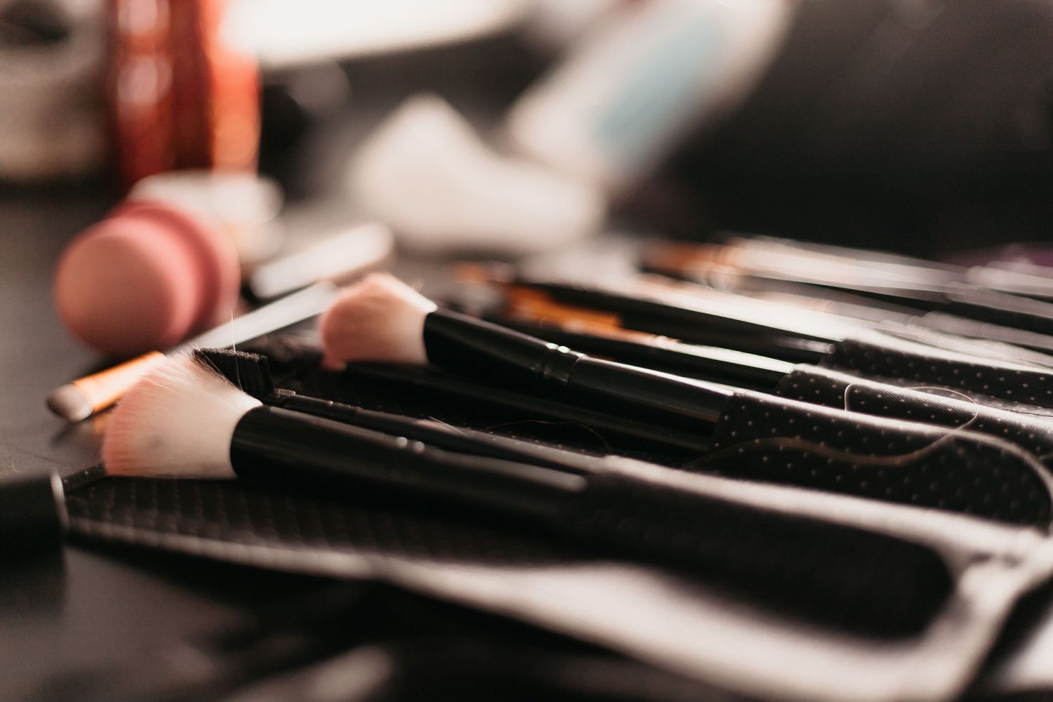 A collection of professional makeup brushes arranged neatly in a black case on a dark surface.