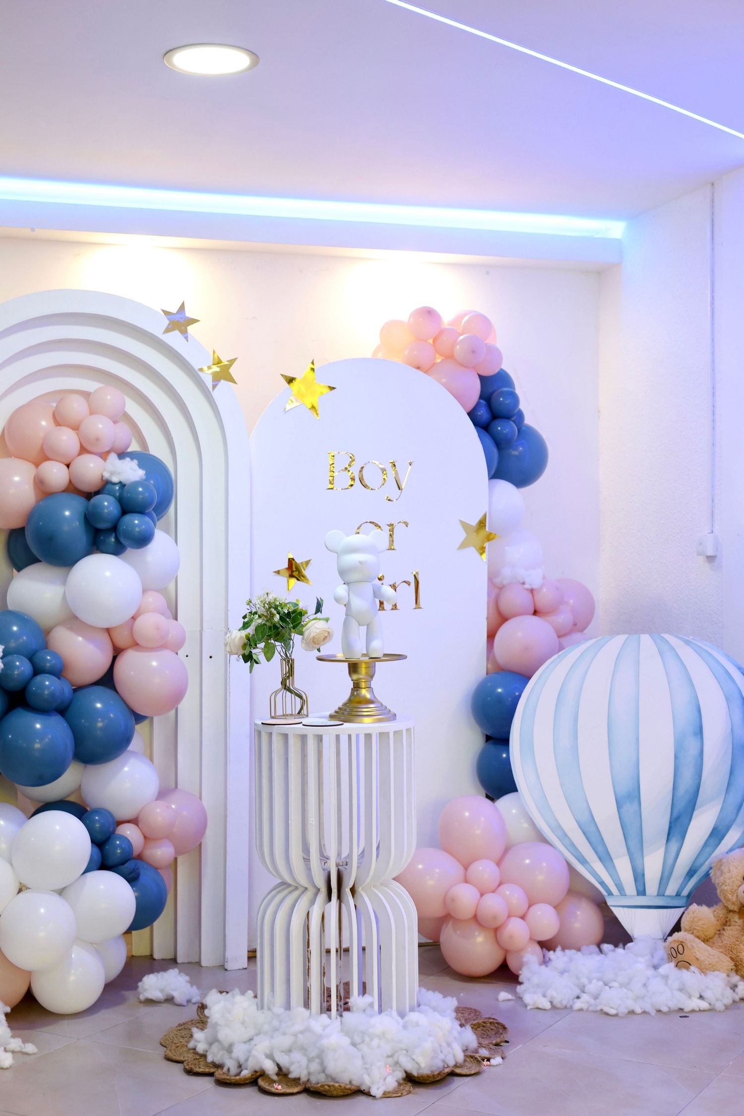 Elegant gender reveal party decoration with pink and blue balloons and a Boy or Girl arch backdrop.