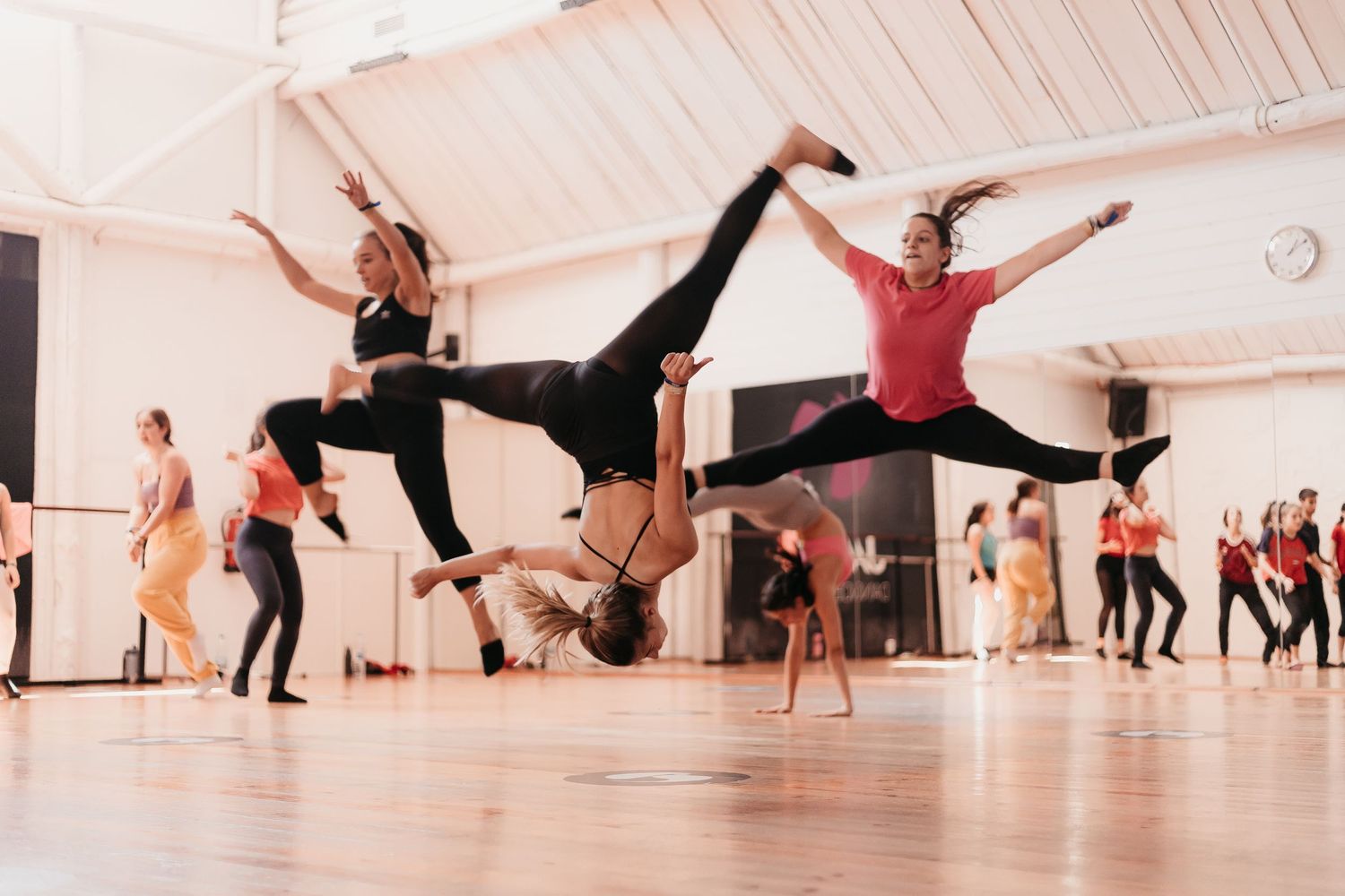 Dynamic dancers perform acrobatic leaps and splits during an energetic rehearsal session.