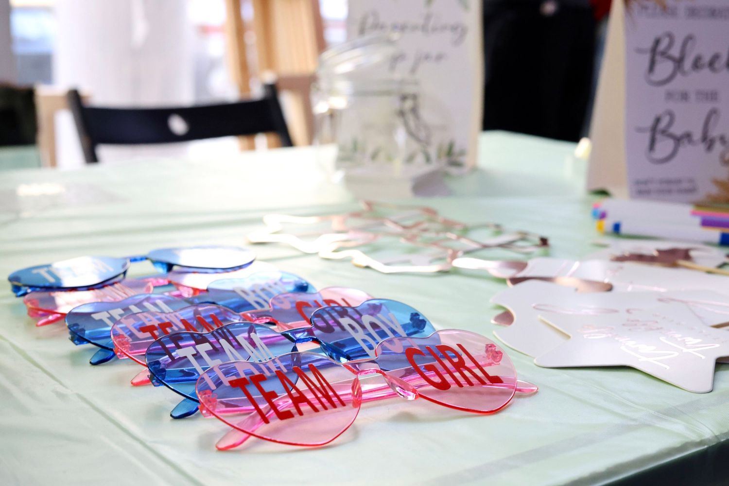 Gender reveal party table with Team Boy and Team Girl acrylic glasses and decorative items.
