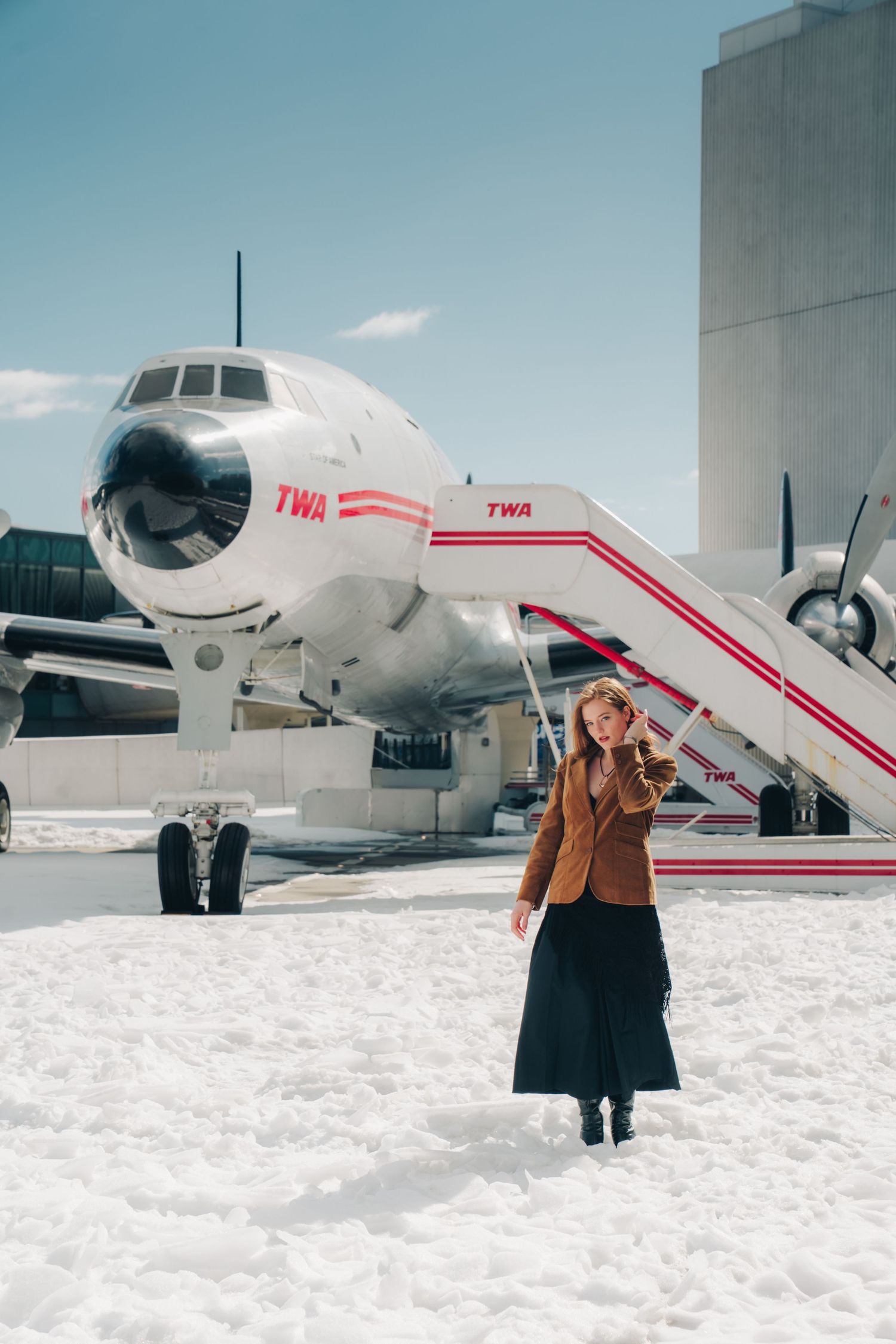 A person poses in front of TWA aircraft on a snowy winter day in a series of vintage-style photos.