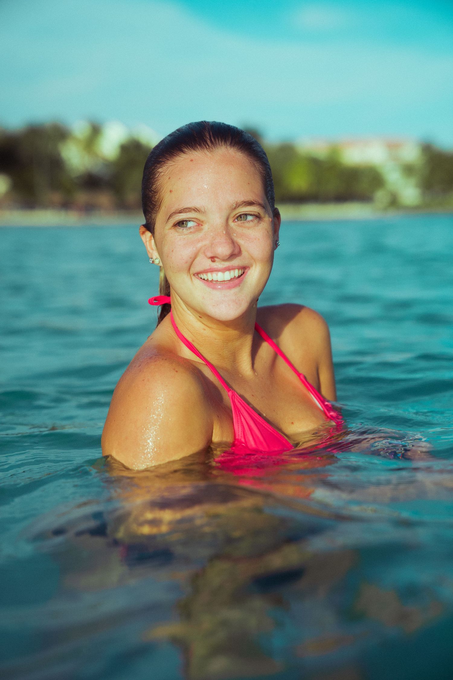 Smiling swimmer in bright pink swimsuit enjoying tropical waters.