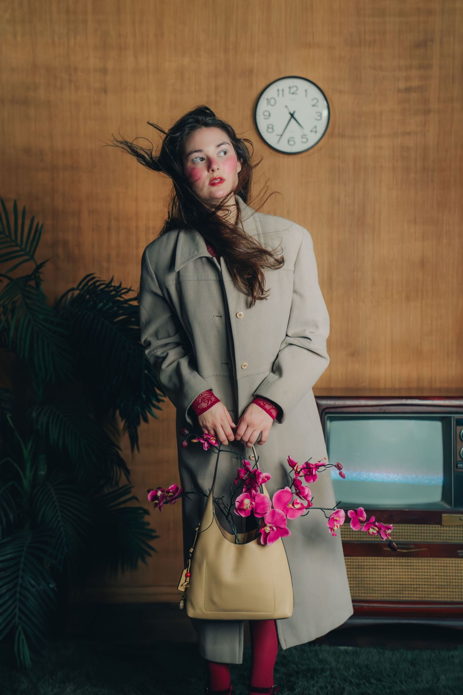 A fashion editorial series shows a model in a beige blazer and pink tights posing expressively against a wooden wall.