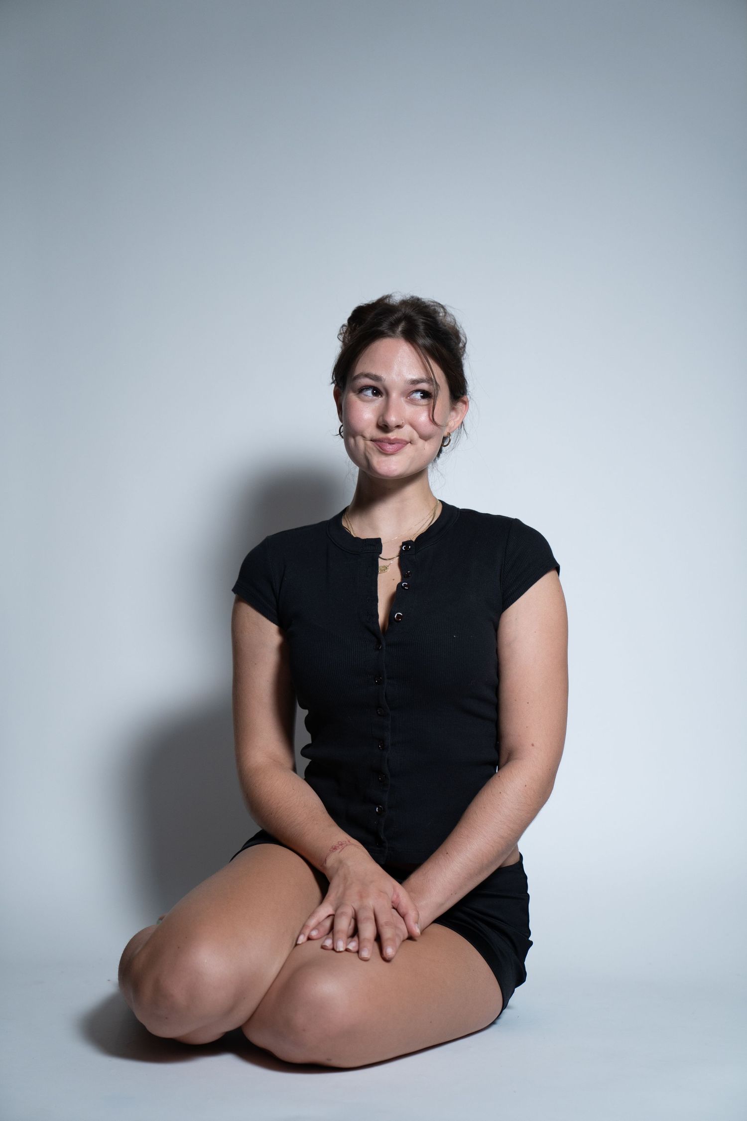 A series of minimalist portraits showing someone in a black top against a light gray background in various seated poses.