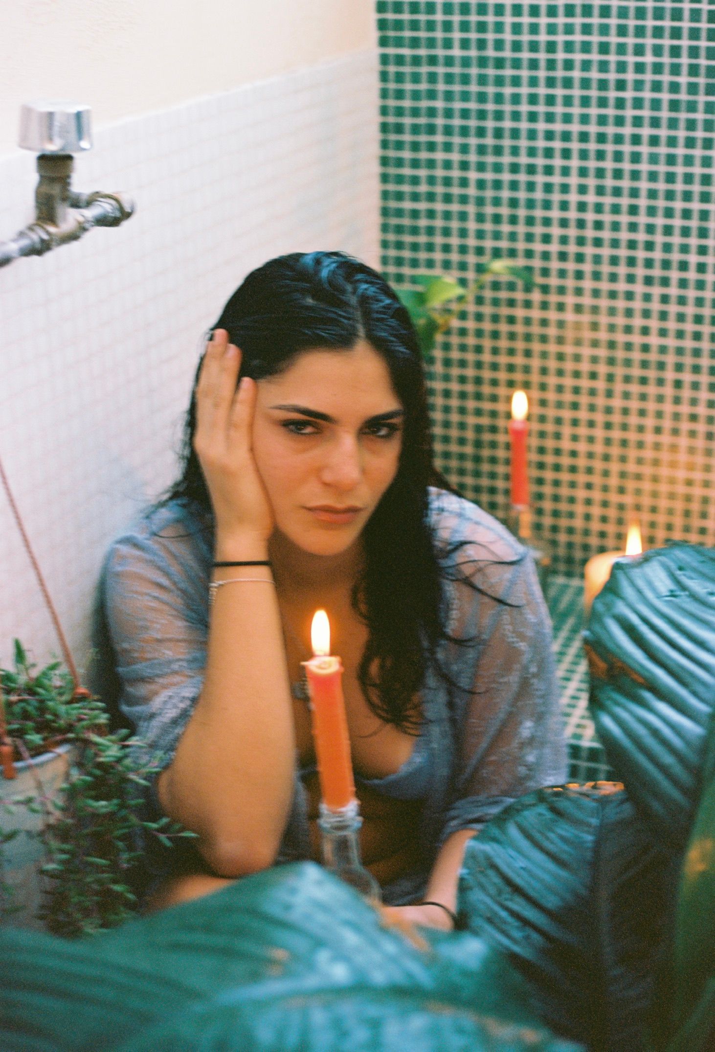 Vintage-style photo with lit candles and green tile bathroom setting creating intimate atmosphere.