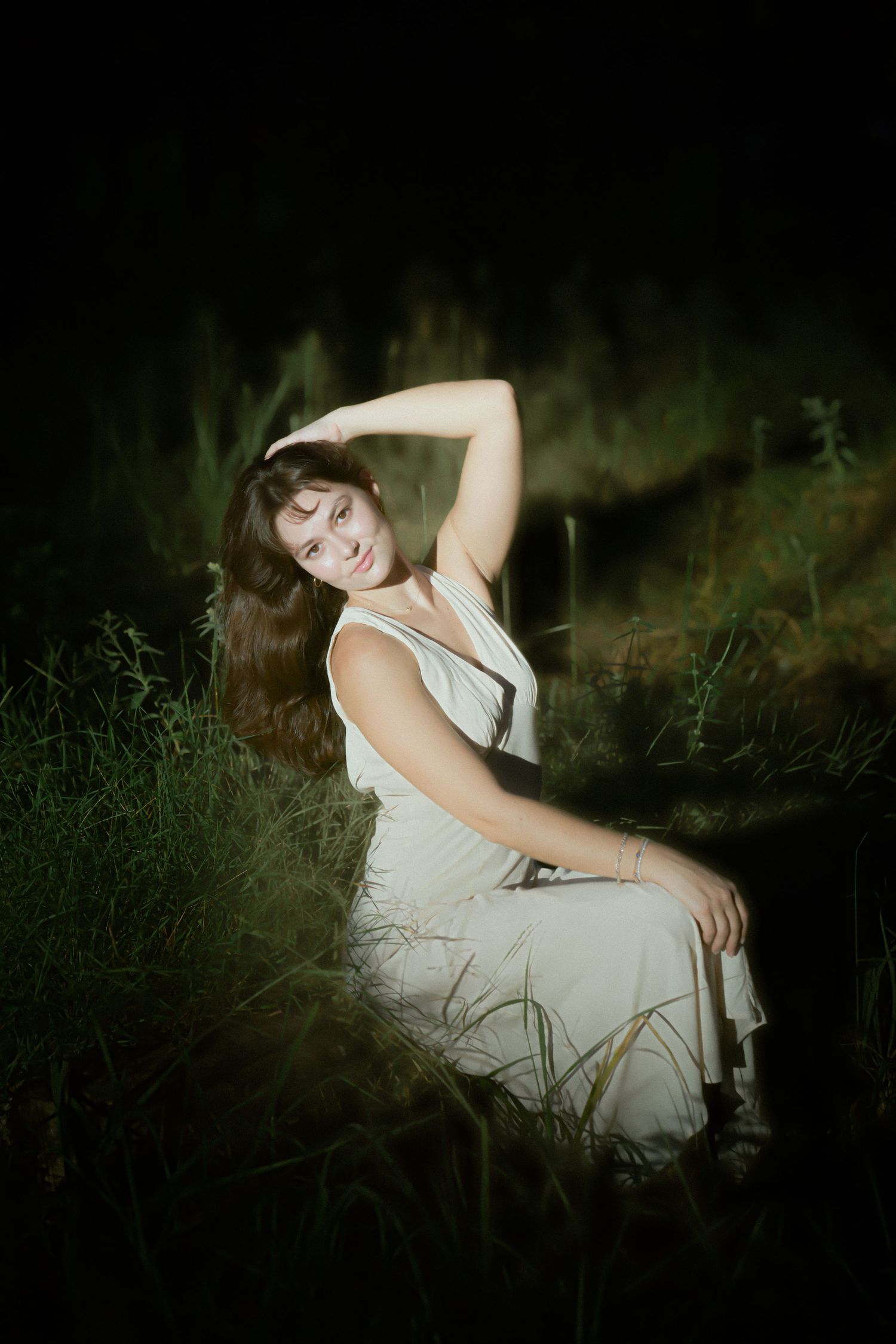 Dramatic evening portrait session in wild grass with ethereal lighting effects.