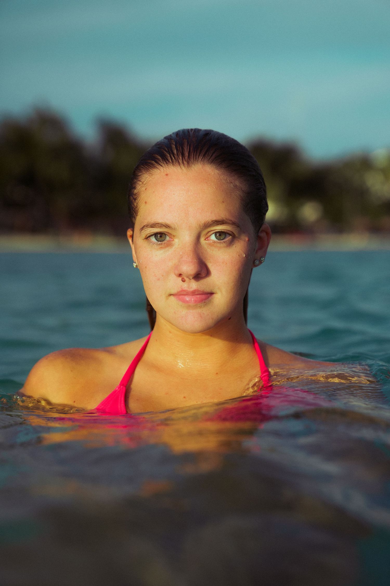 Portrait of swimmer in red swimsuit emerging from tropical waters.