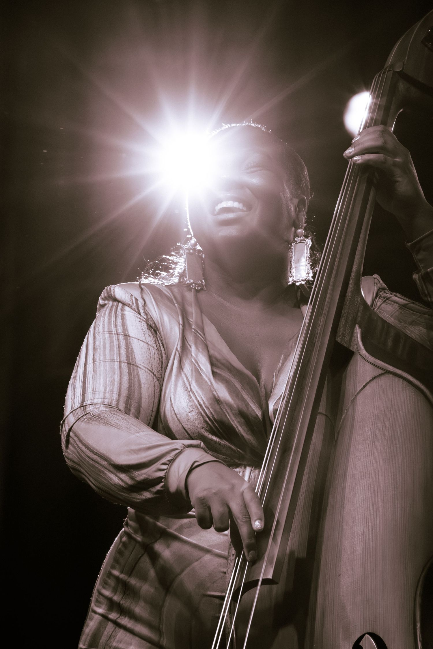A jazz musician plays upright bass in dramatic lighting during a performance.