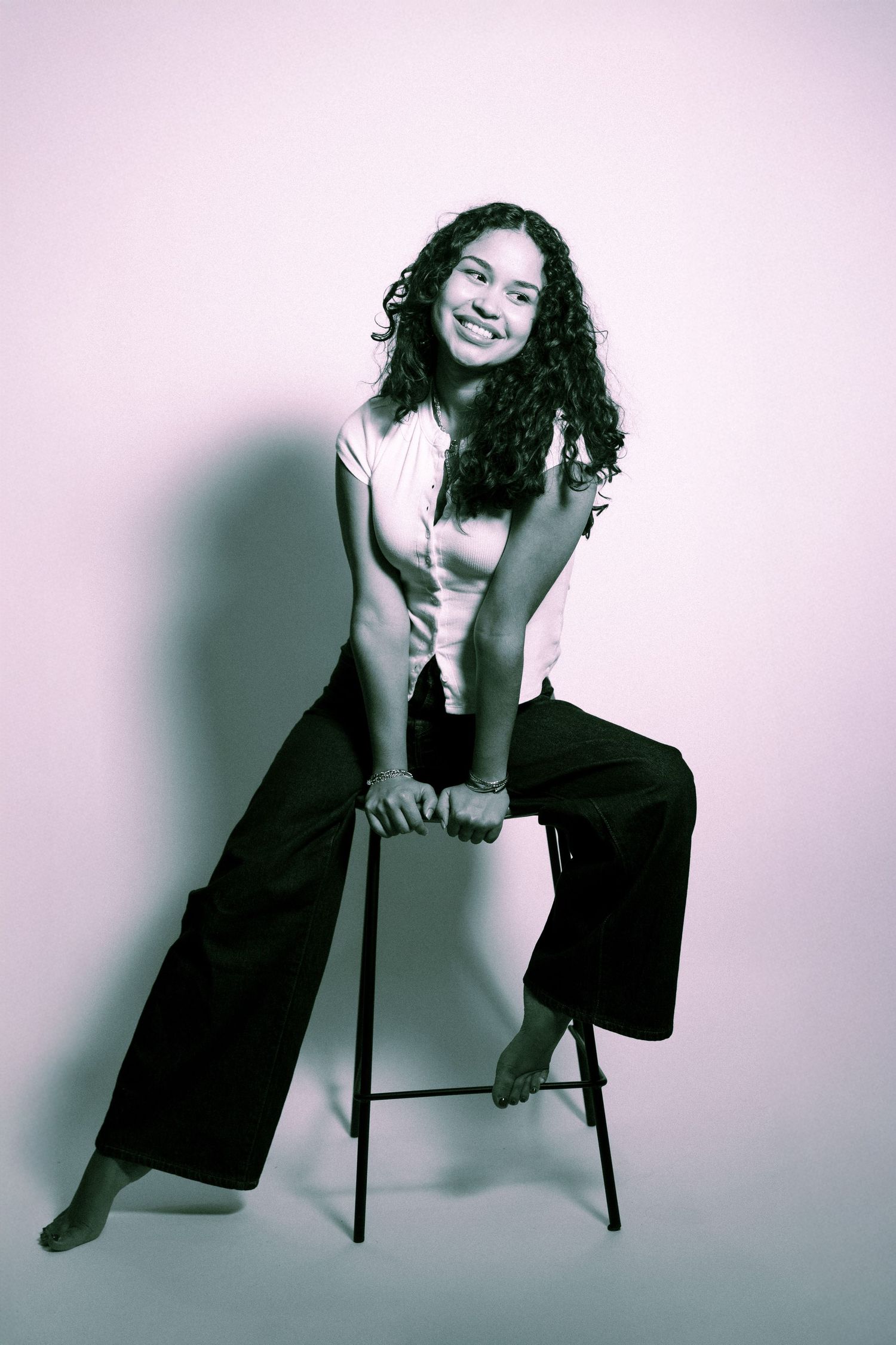 Four black and white fashion portraits show a person in dark clothing posing dramatically with a chair against a light backdrop.