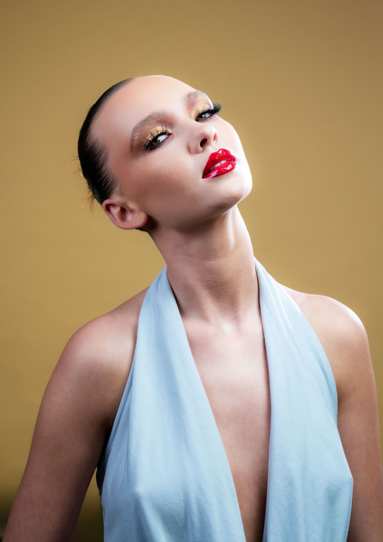 Fashion portrait series showing a model in a light blue halter top posing dramatically against a beige background.