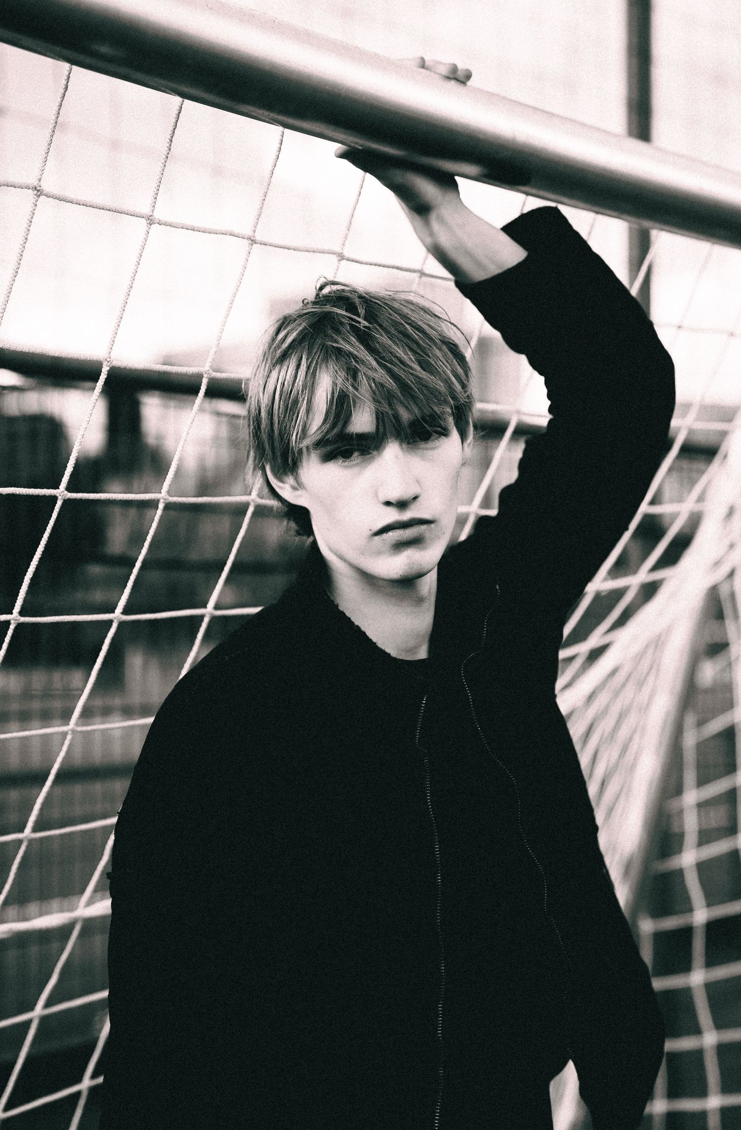 Artistic black and white photo series showing moody figures in dark clothing against white geometric background.