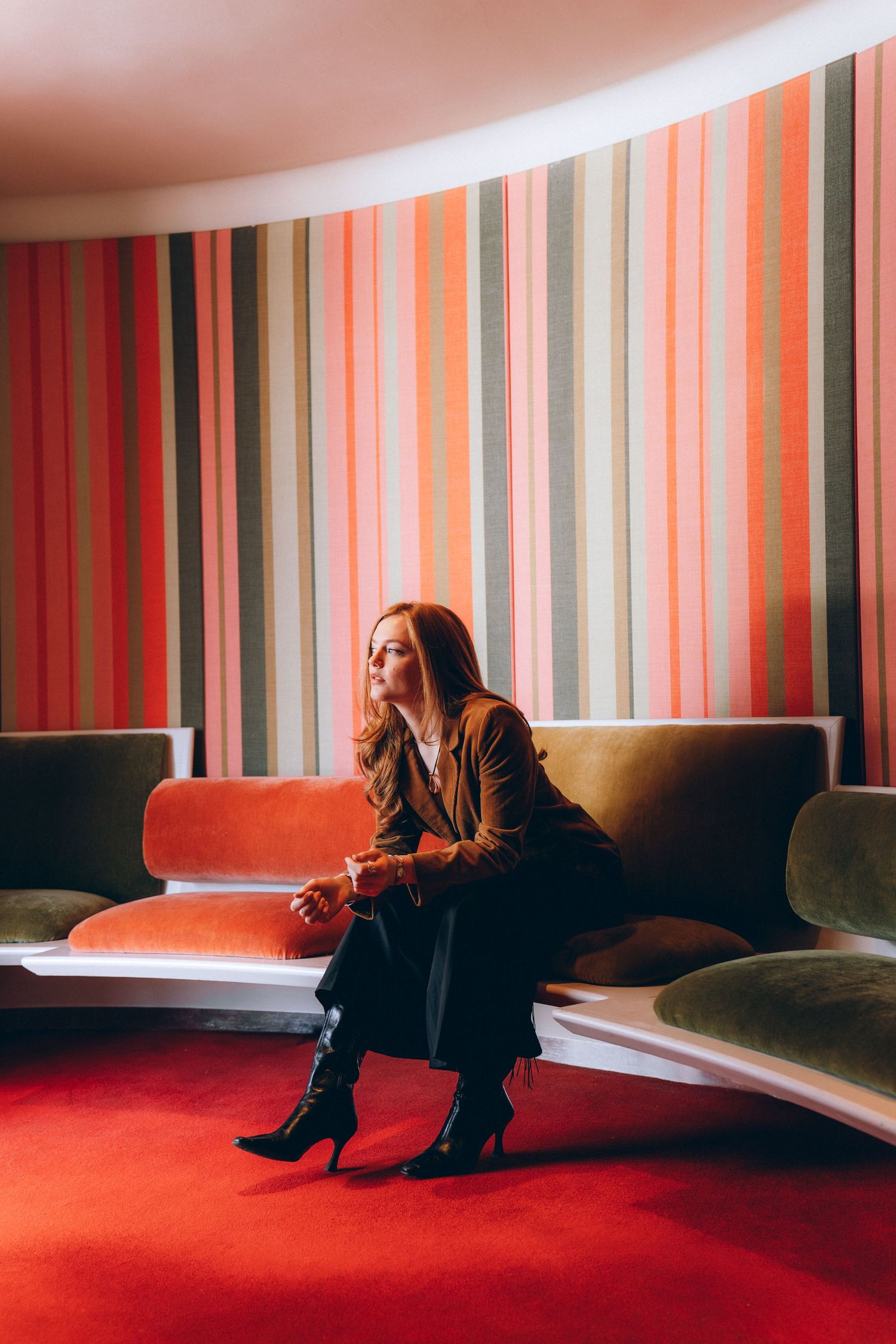 A sequence of photos showing a person sitting alone in a room with red carpet and striped wallpaper creating a moody atmosphere.