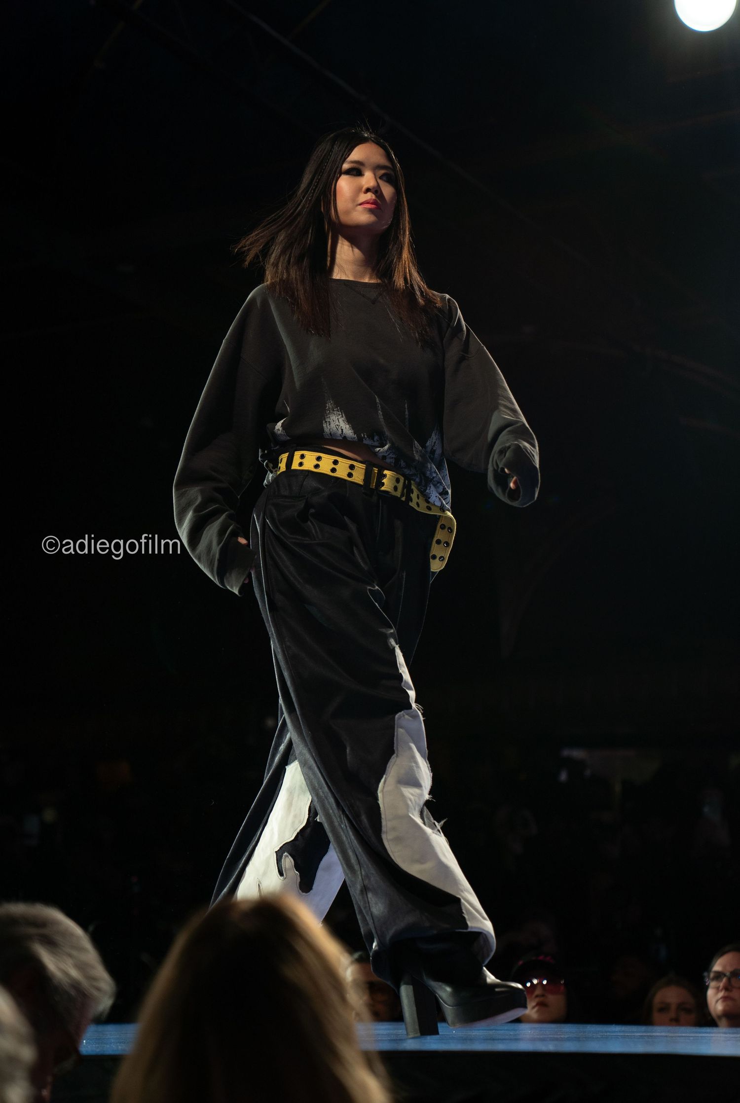 Performer in a dark jersey and light pants dances energetically on stage during a nighttime performance.