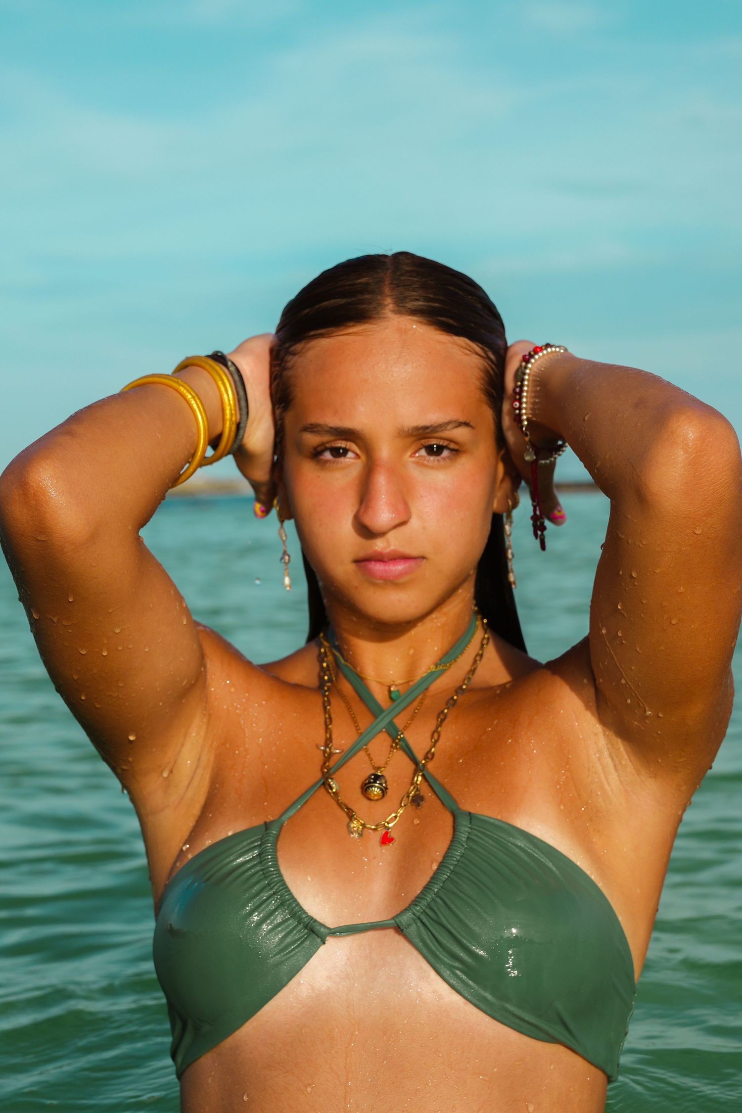 Portrait of swimmer with wet hair and jewelry in turquoise water.