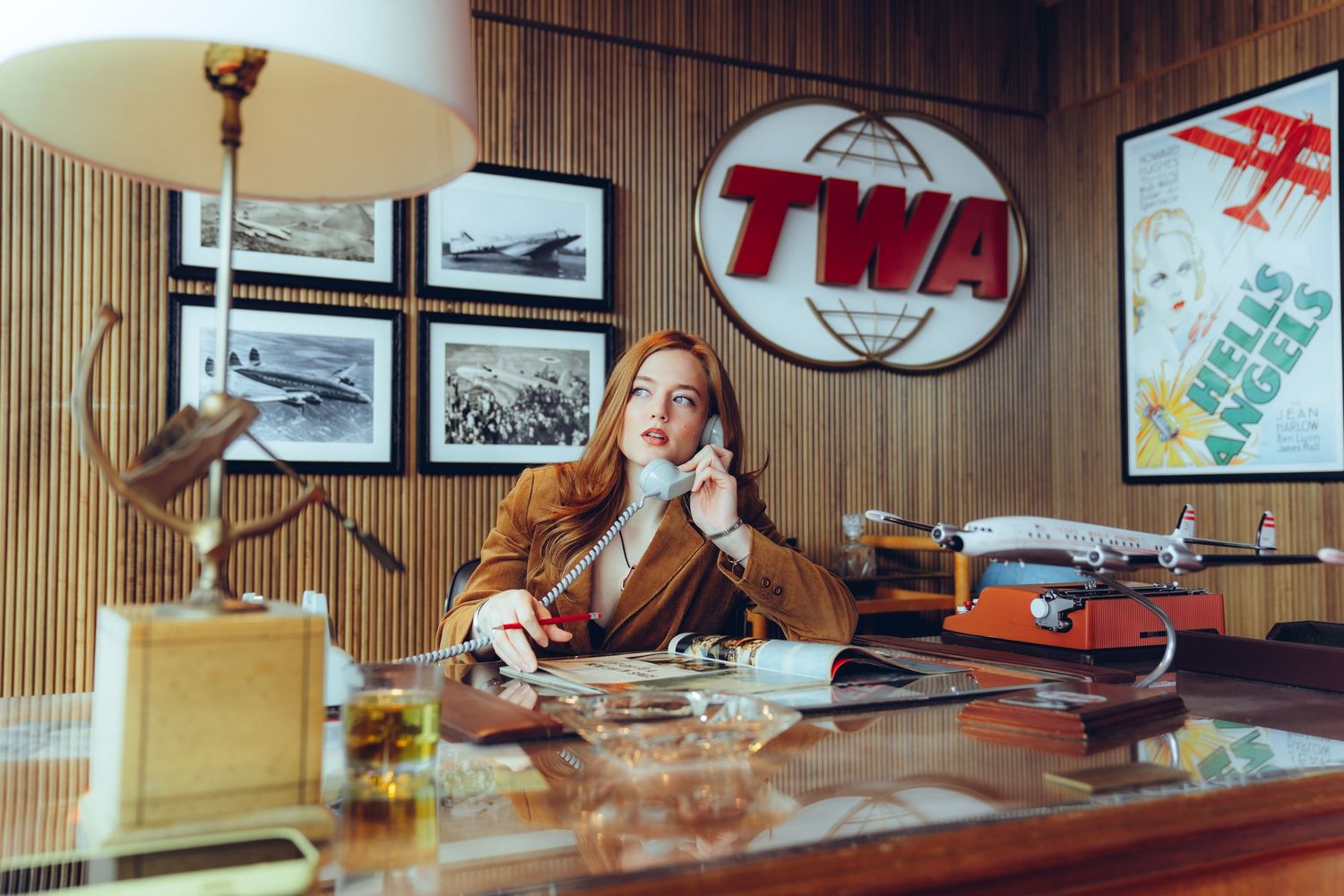 Vintage wood-paneled office interior with retro furniture, desk lamps, and framed artwork on the walls.