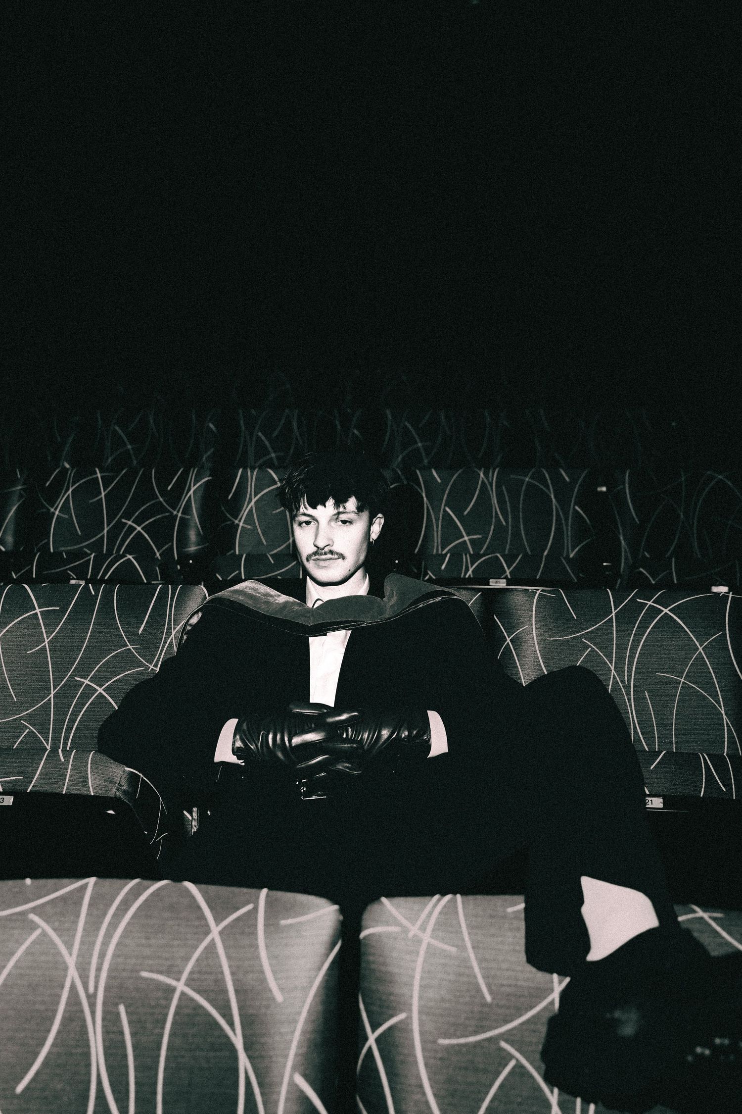 Two figures in black attire pose against a dark background with white graffiti-style markings.