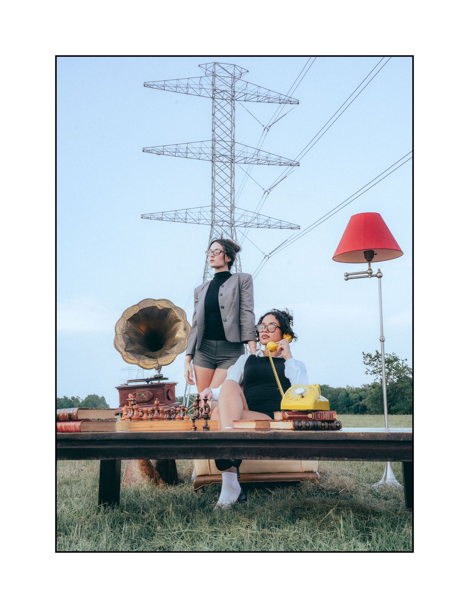 A vintage-styled scene with antique phonograph and red lampshade set against electrical towers in the background.