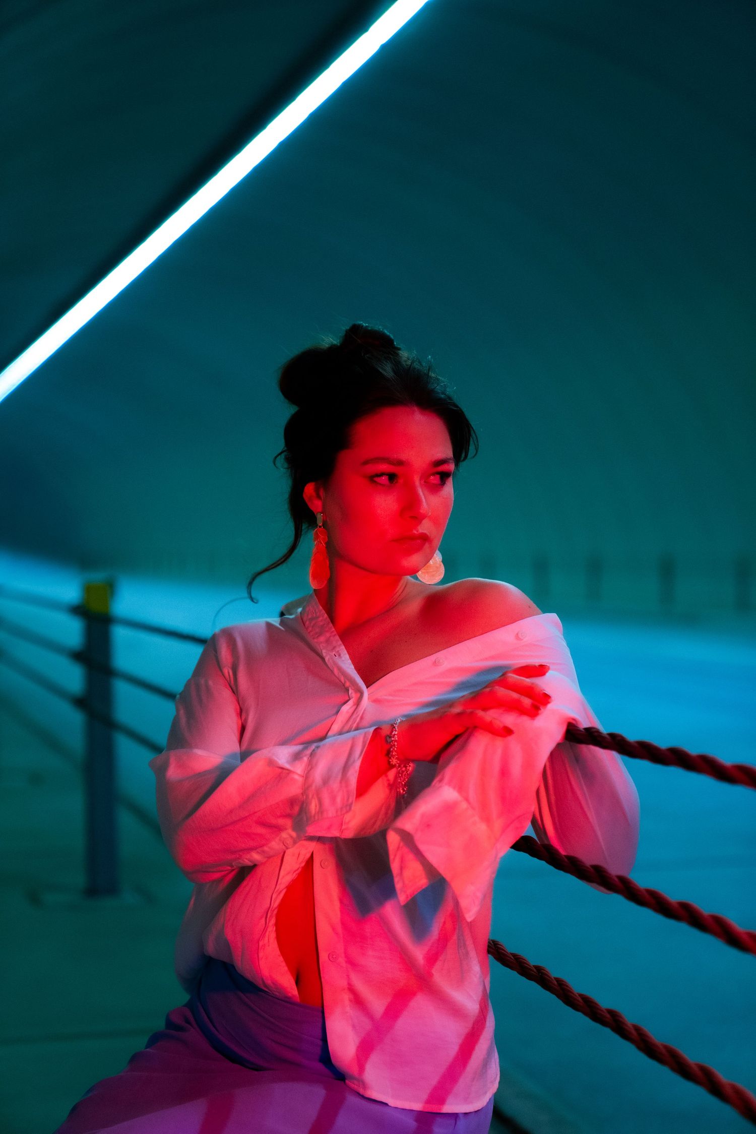 Artistic portrait in neon lighting with teal and pink hues creating a moody atmospheric effect.