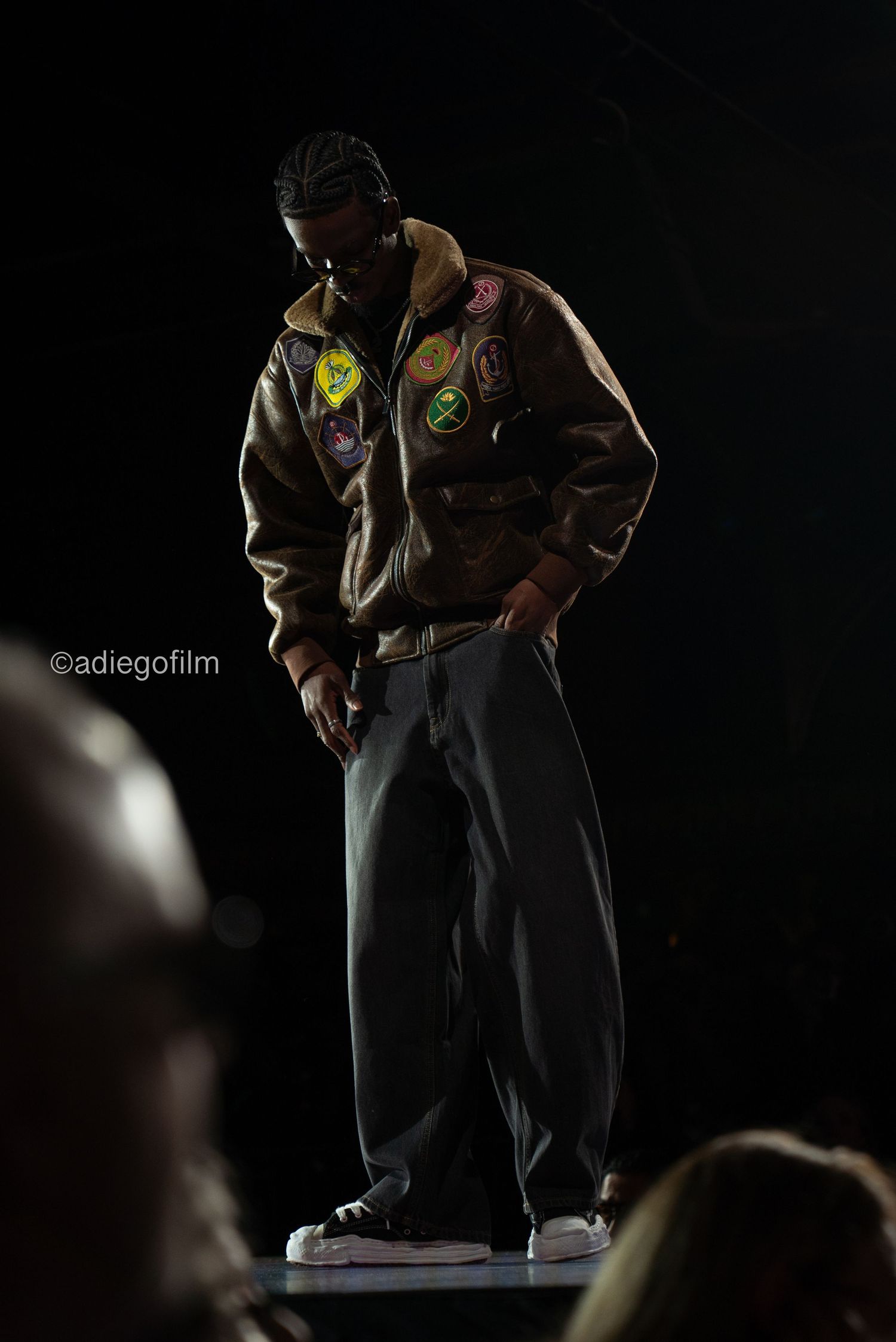 Dramatic low-angle shot of a figure performing on a dark stage with dramatic lighting and shadows.
