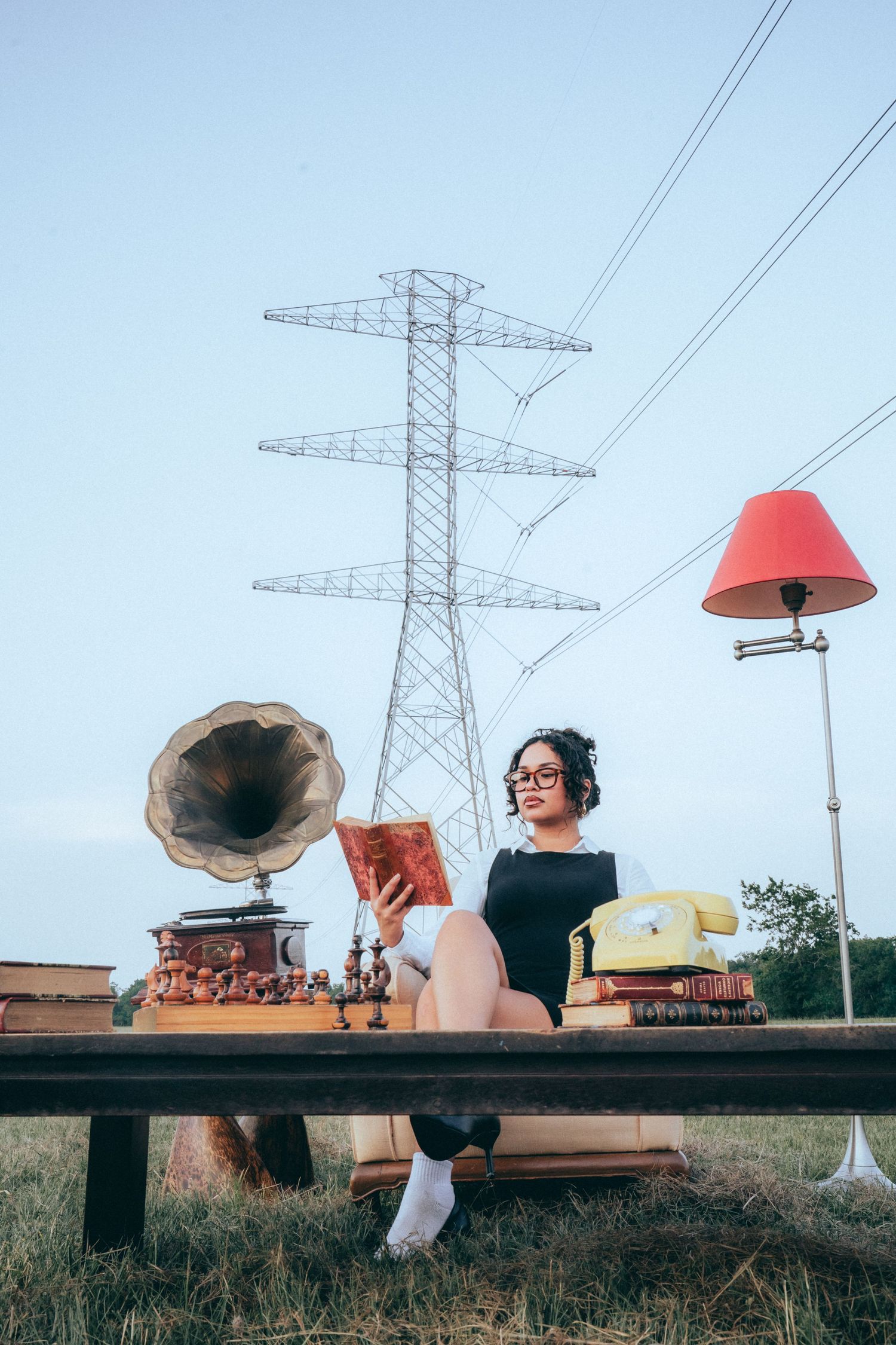 Retro scene with vintage phonograph, table lamp, and electrical tower in background under blue sky.
