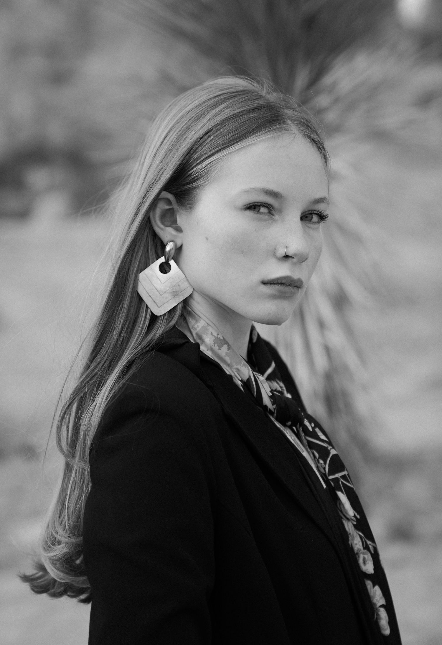 A black and white fashion portrait series showing a person in a dark coat against a soft blurred background.