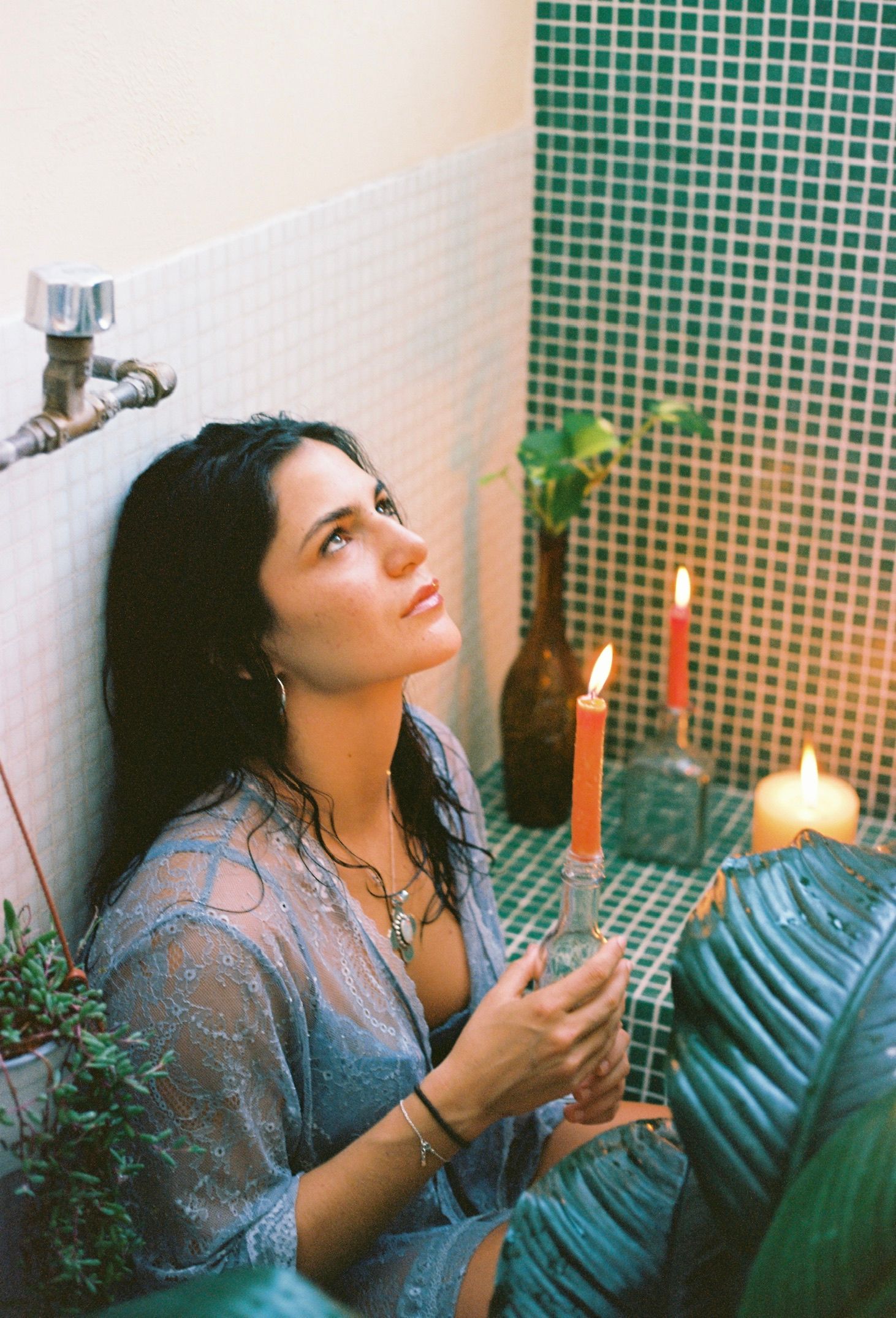 Atmospheric bathroom scene with candlelight, plants, and white tile creating serene mood.