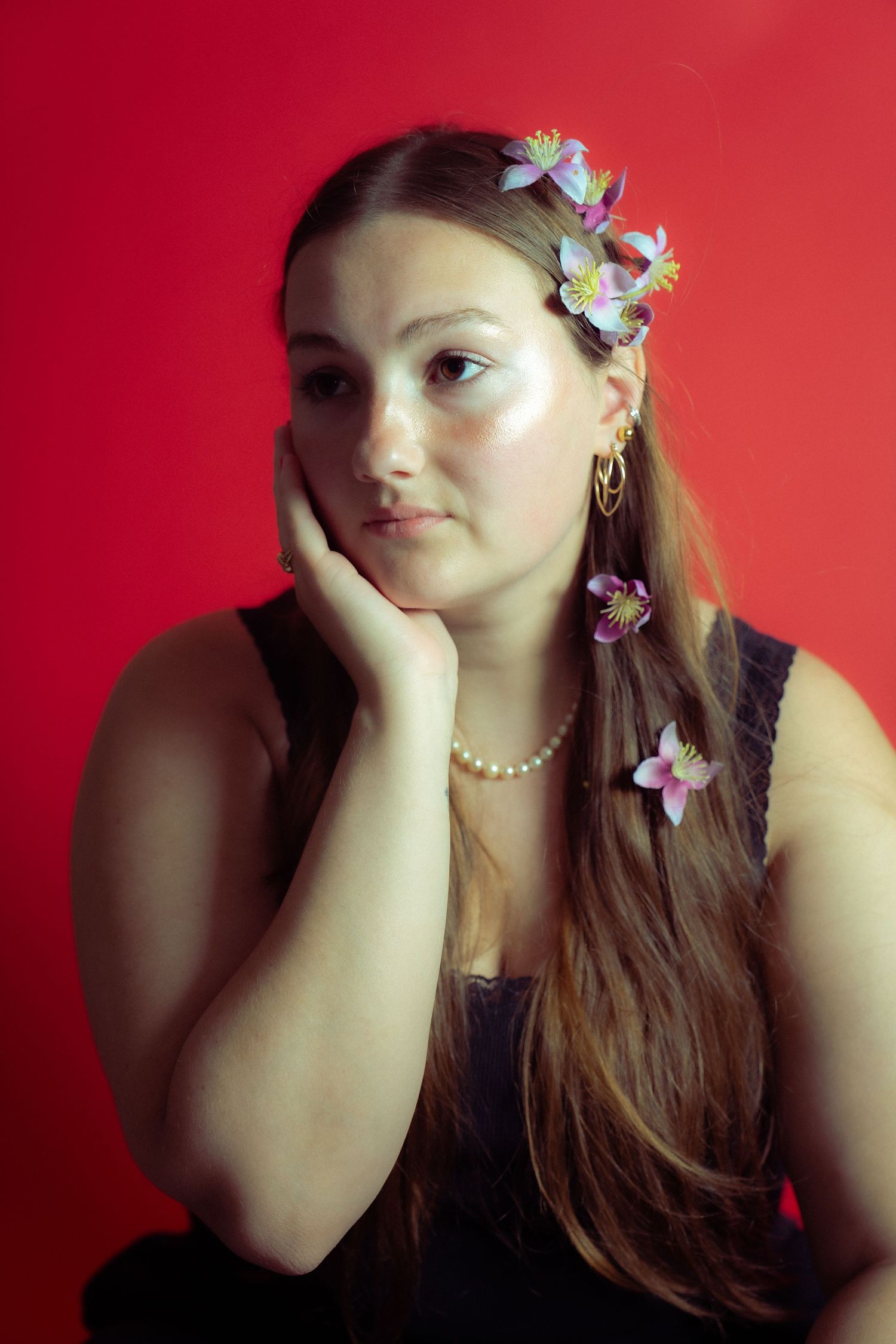 A collage showing poses against a red background with long brown hair adorned with delicate floral hair accessories.