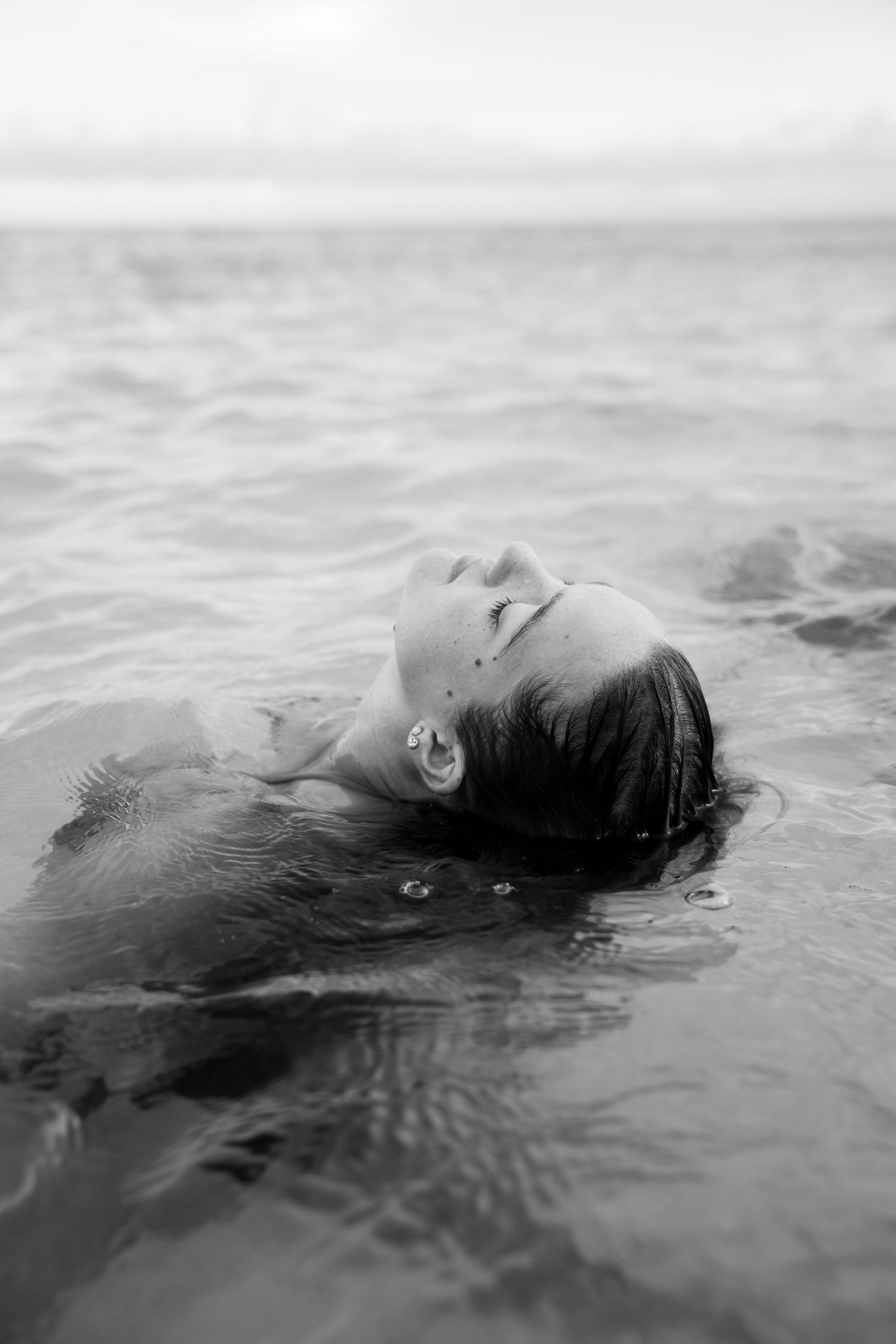 Artistic black and white photo of someone floating peacefully in calm waters.
