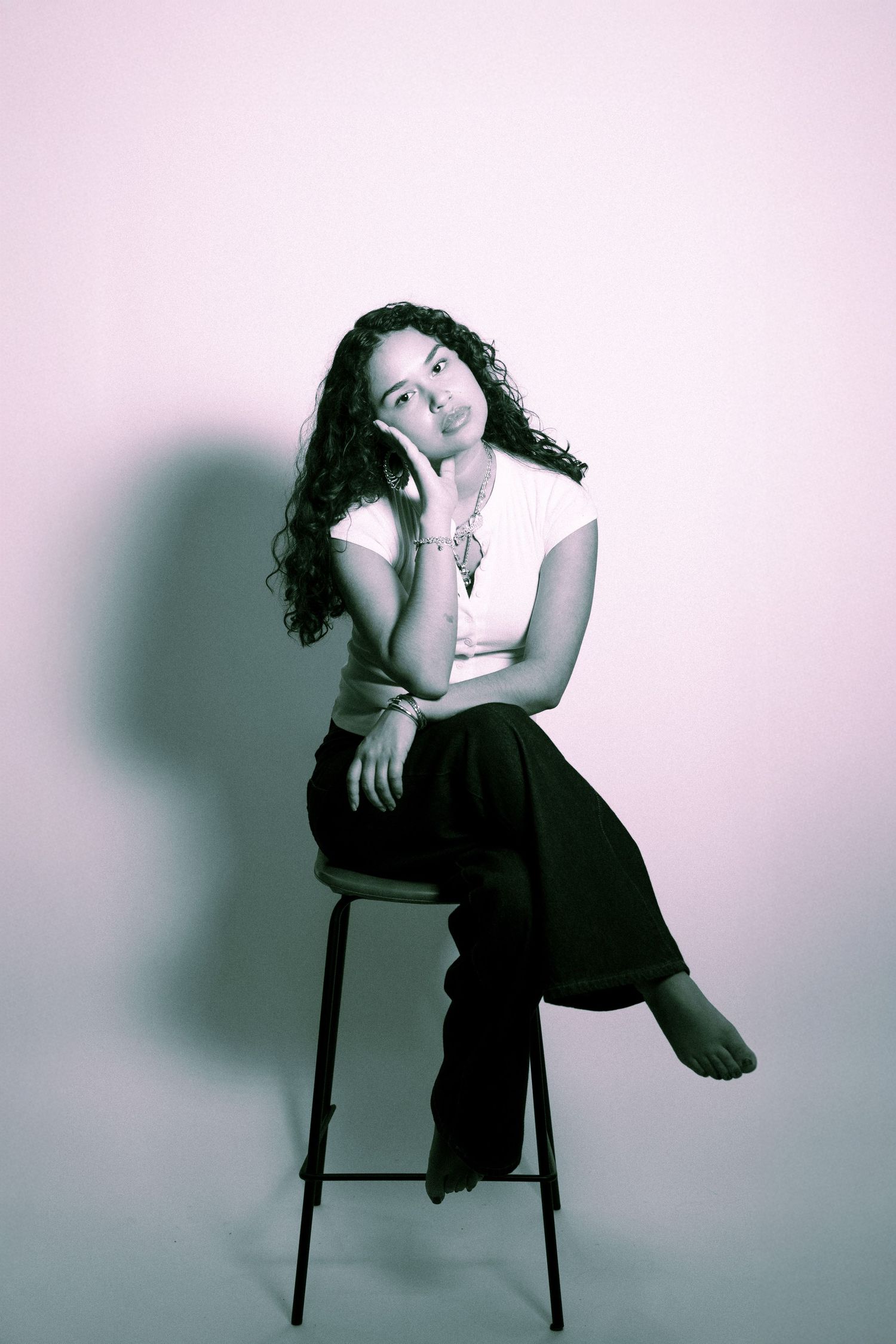 Artistic black and white portrait series showing graceful poses of person in dark clothing seated on chair with shadow.