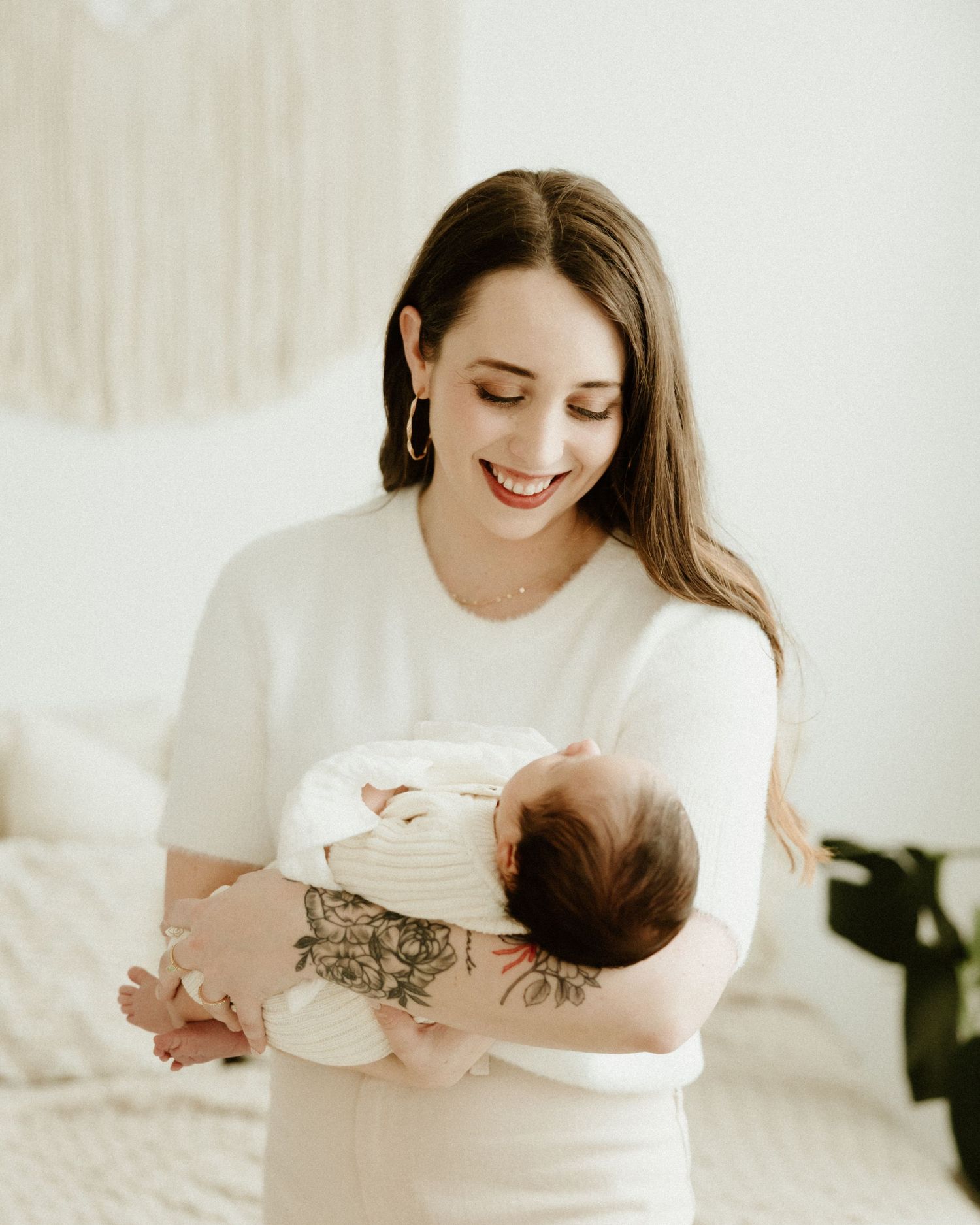 A series of soft, minimalist photos showing tender moments between parent and newborn in a bright white setting.