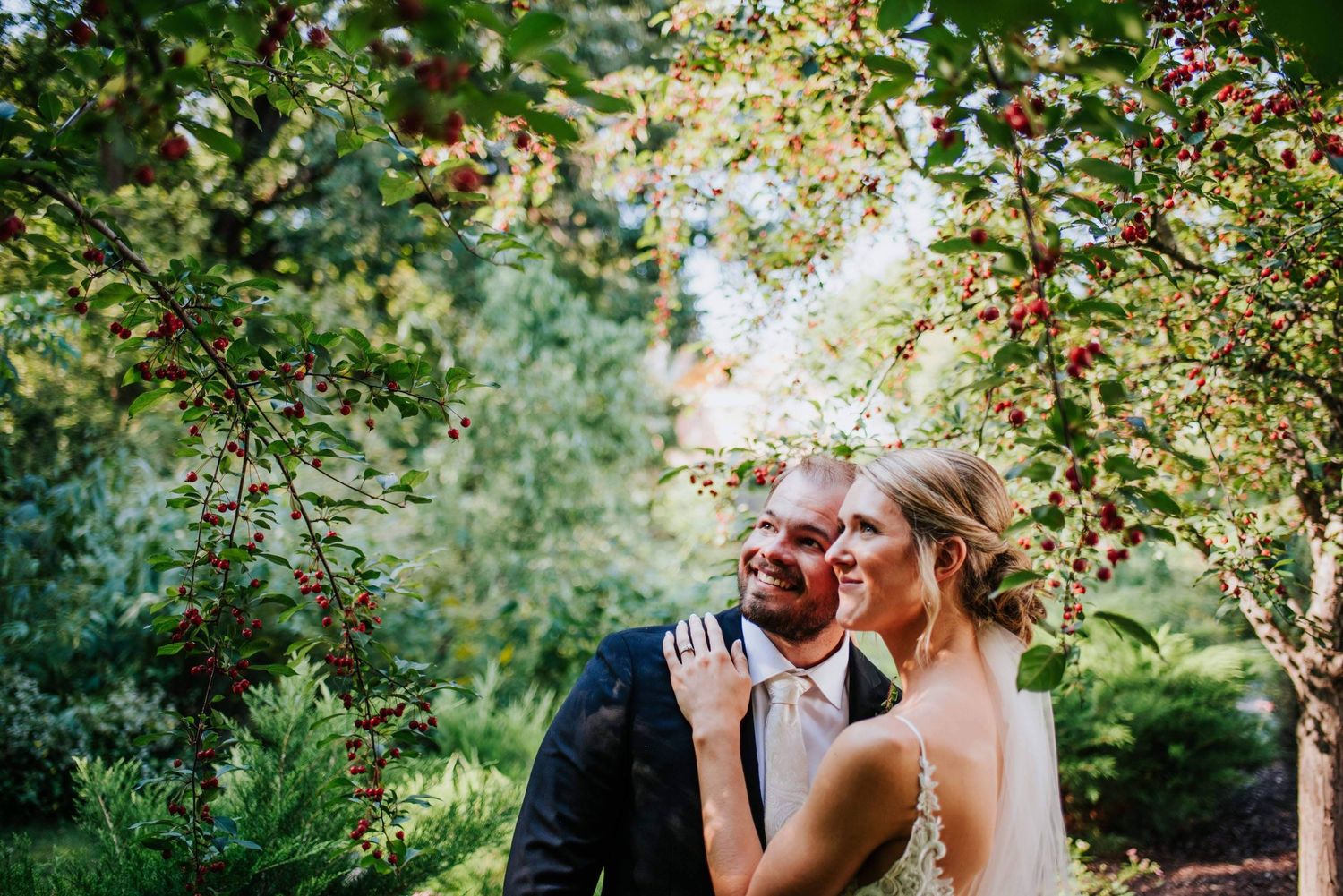 Romantic outdoor wedding photoshoot among blooming trees and natural greenery.
