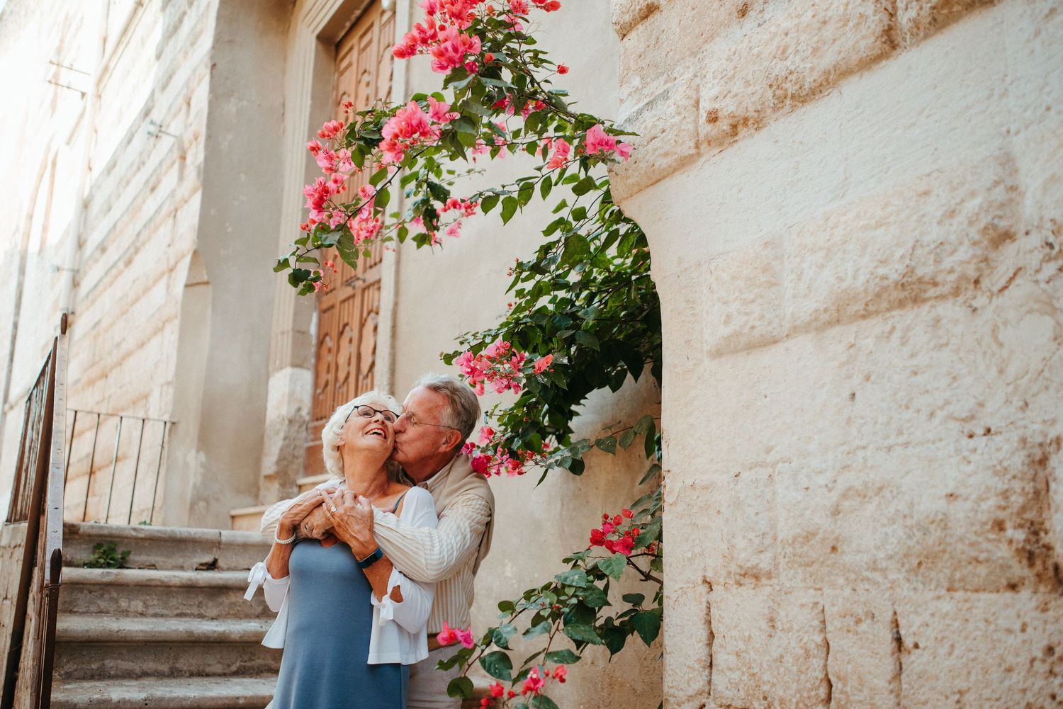 Couple embracing near stone wall with blooming pink roses.