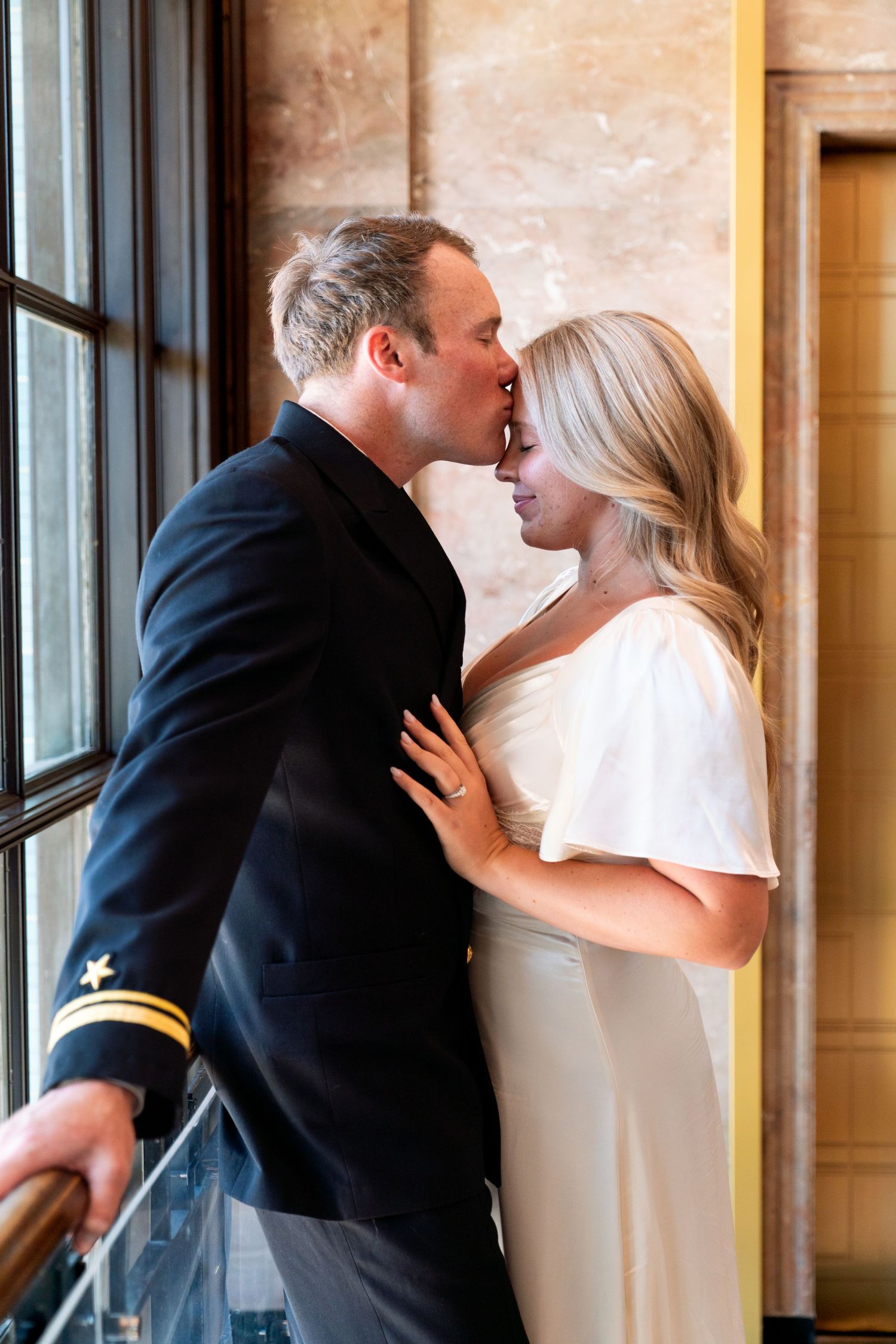 A progression of three photos showing a romantic first kiss between newlyweds at their wedding ceremony.