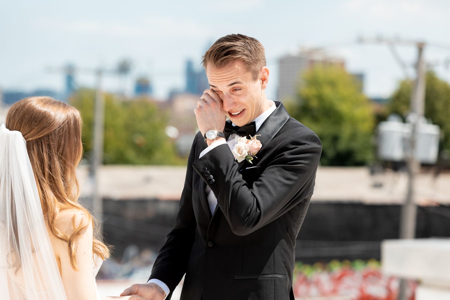 An emotional moment between a couple during their wedding ceremony with a city skyline in the background.