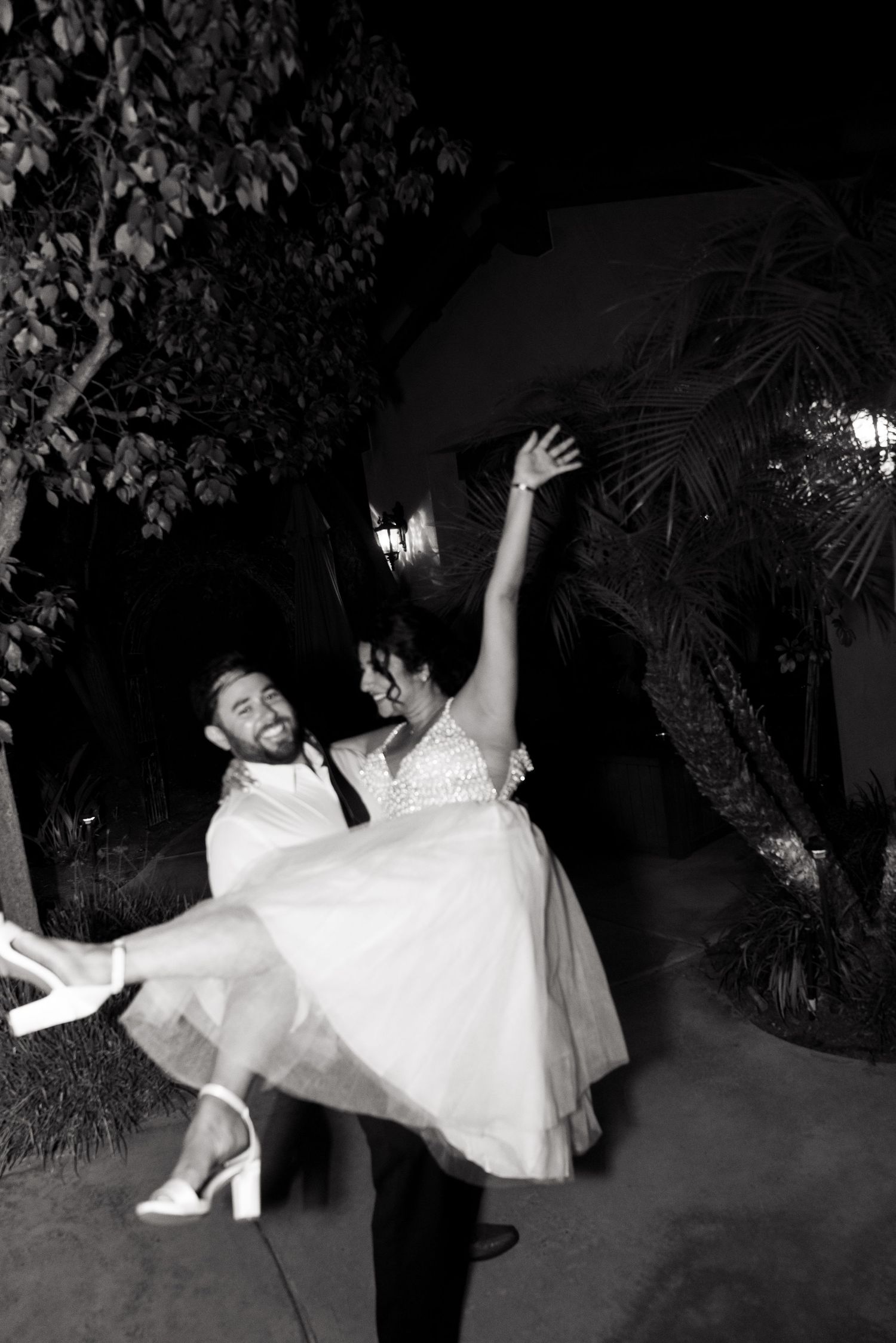 A black and white wedding photo captures a romantic dip dance pose between newlyweds on their special night.