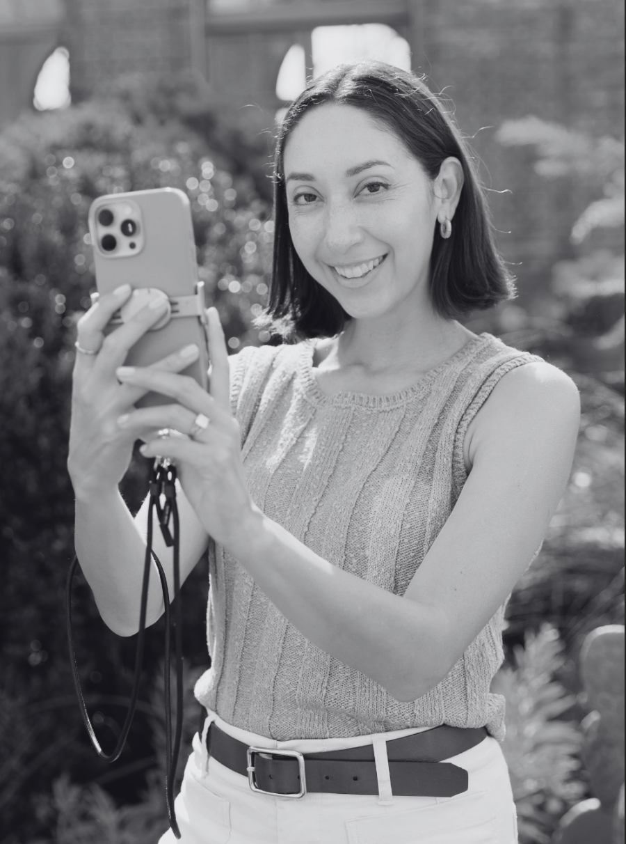 Woman in a sleeveless silver sequined top takes outdoor mirror selfies in a sunny garden setting.