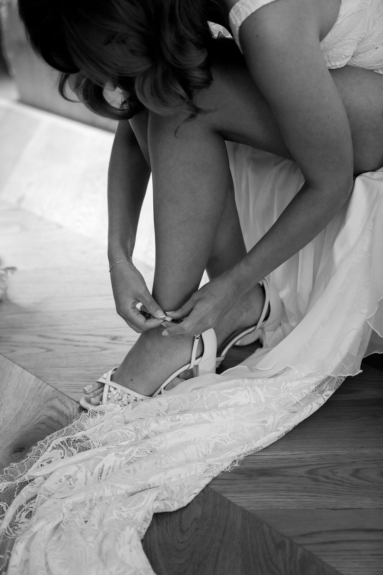 Four sequential photos showing someone putting on strappy white wedding shoes against a hardwood floor.