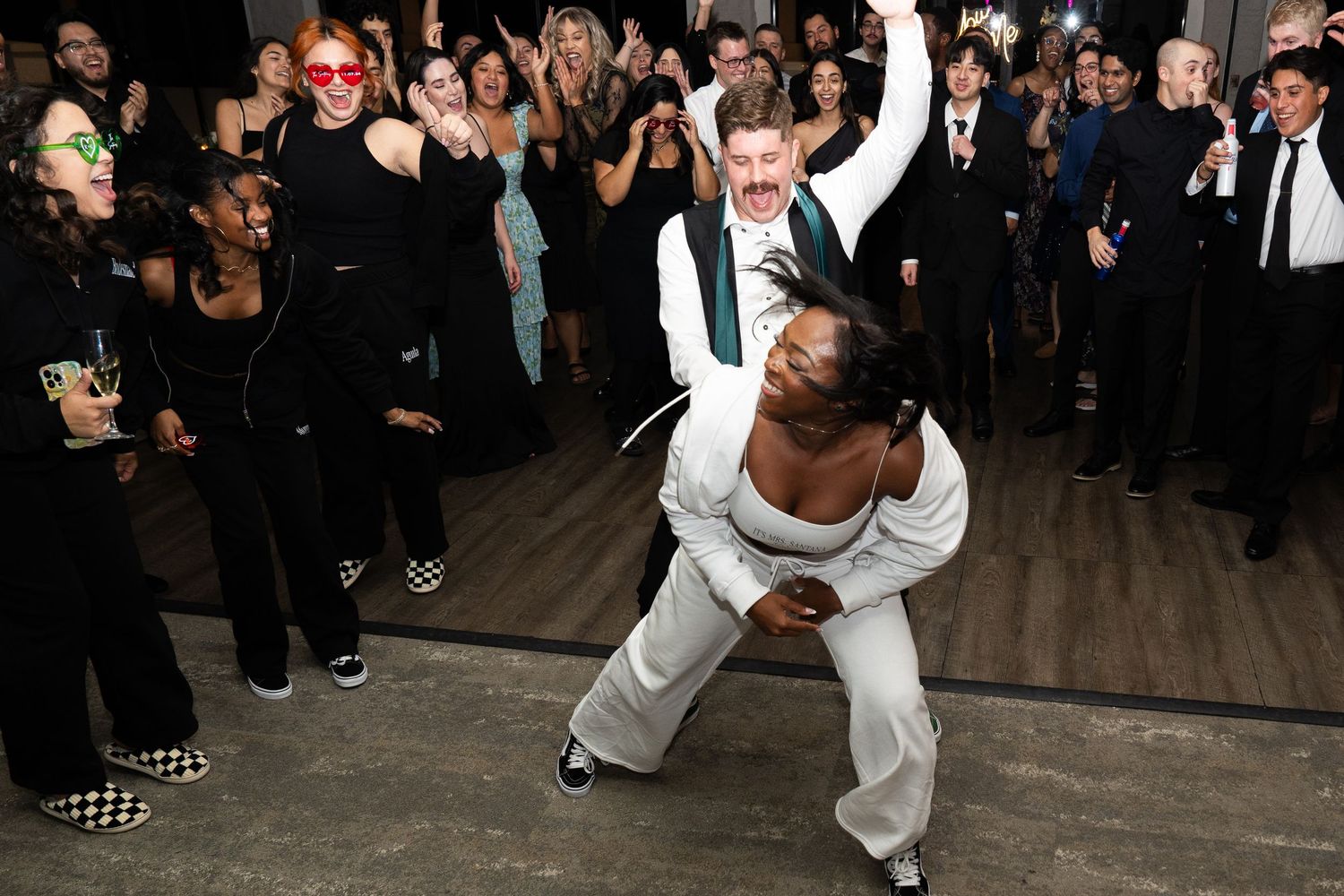 Wedding guests enjoying themselves on a dance floor with dramatic dance moves at a celebration reception.