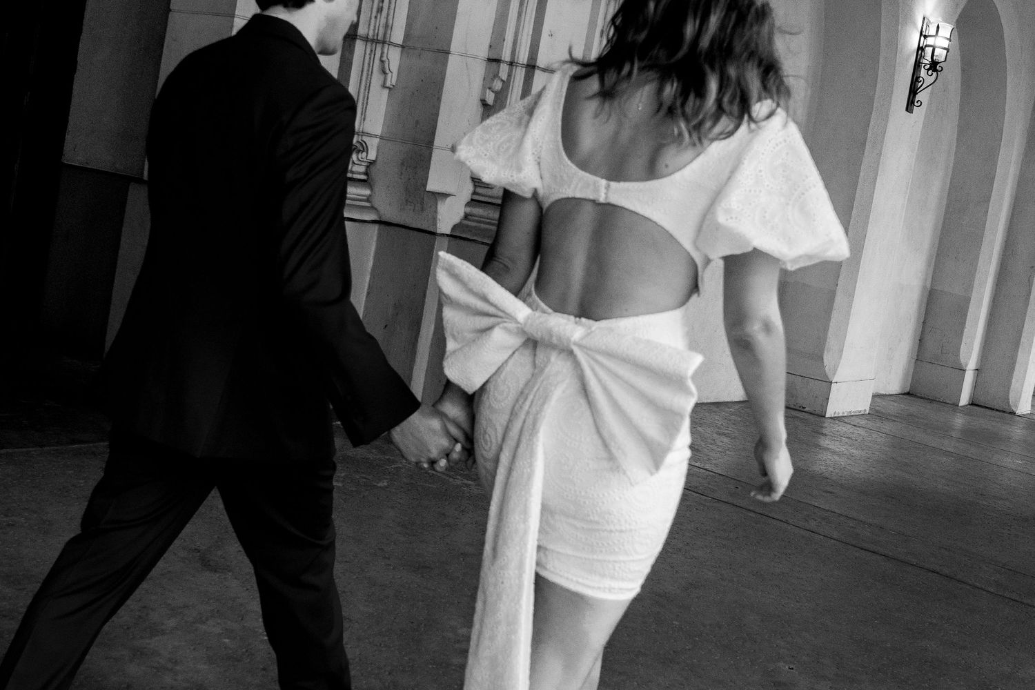Black and white photo of a couple dancing together, with the woman wearing a white dress with cutout detail.