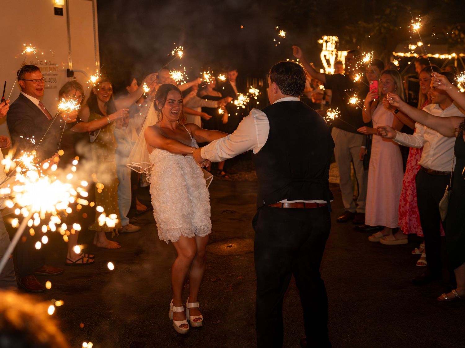 Photography of bride and groom in sparkler exit with friends and family after an elegant New England wedding reception in New Hampshire