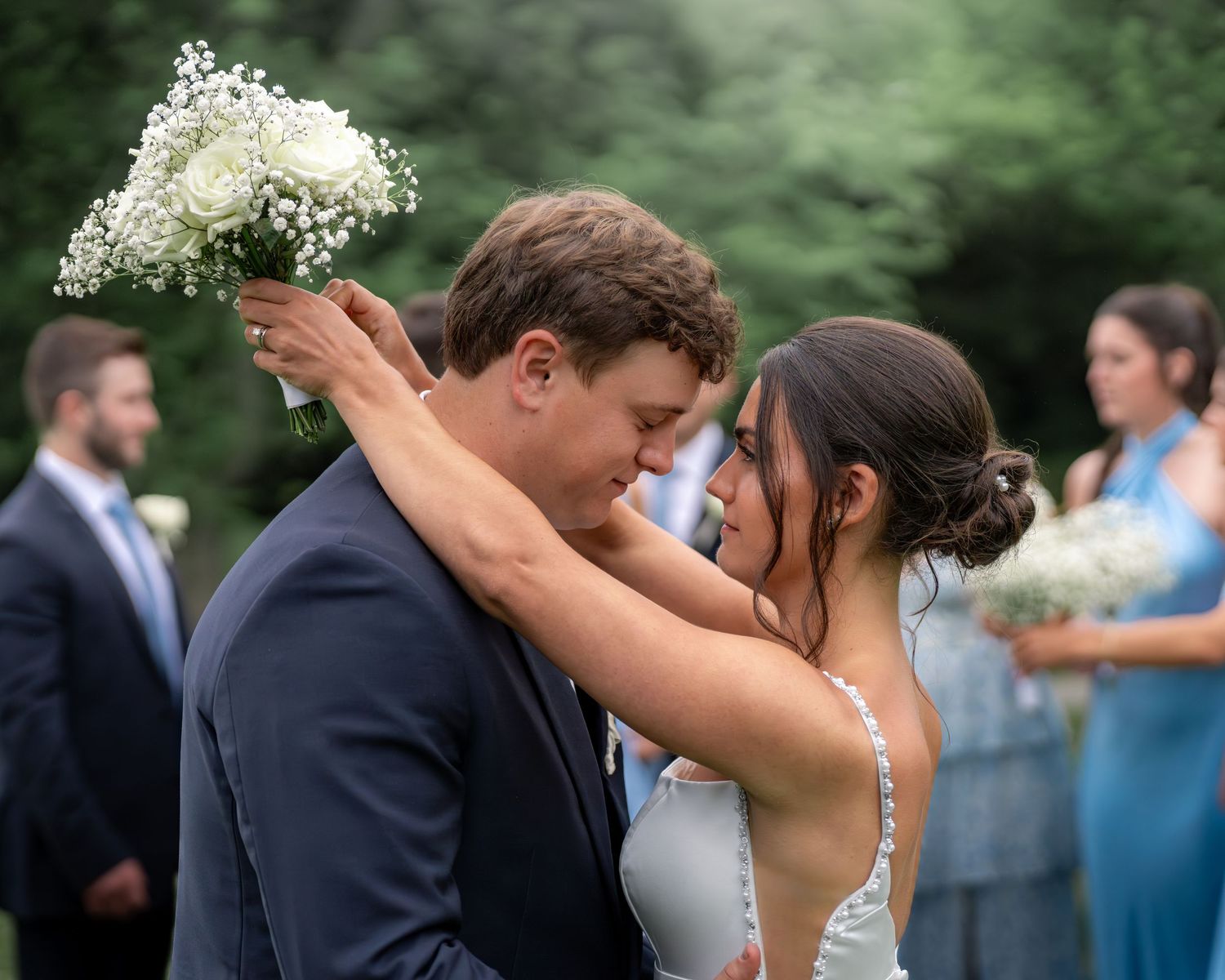 Photography of bride and groom share a dramatic first kiss after an elegant New England wedding ceremony celebration with wedding party