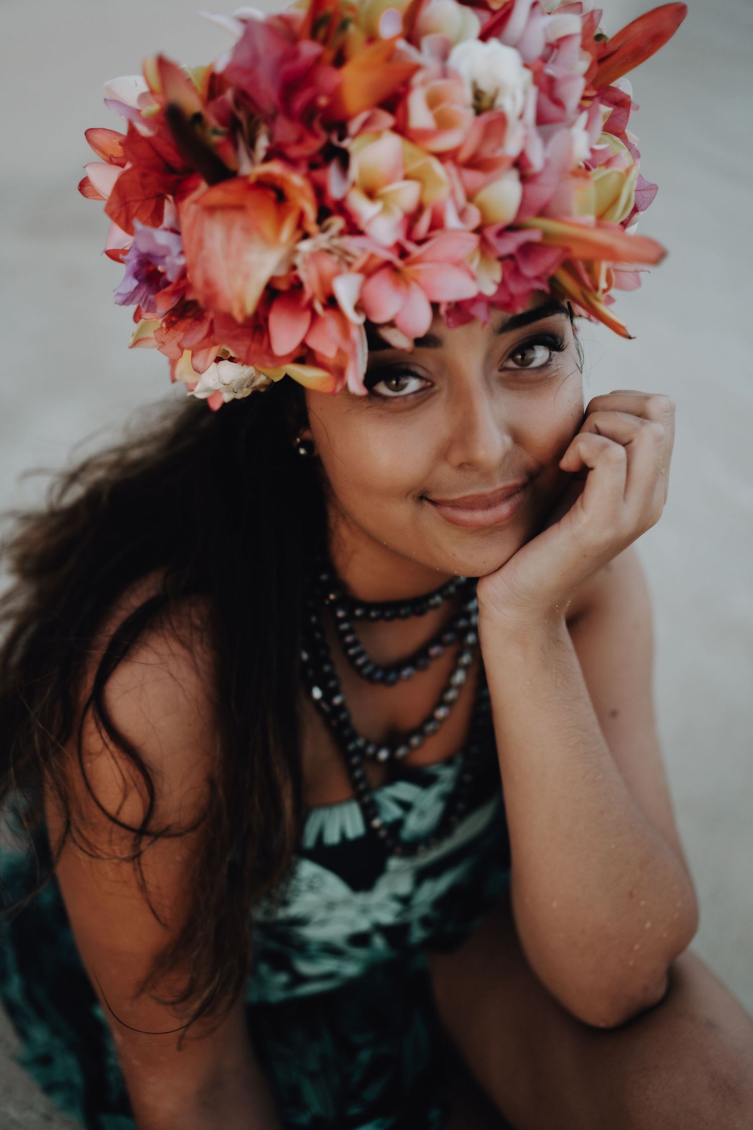 Portrait wearing vibrant pink and orange floral crown with black beaded necklace.