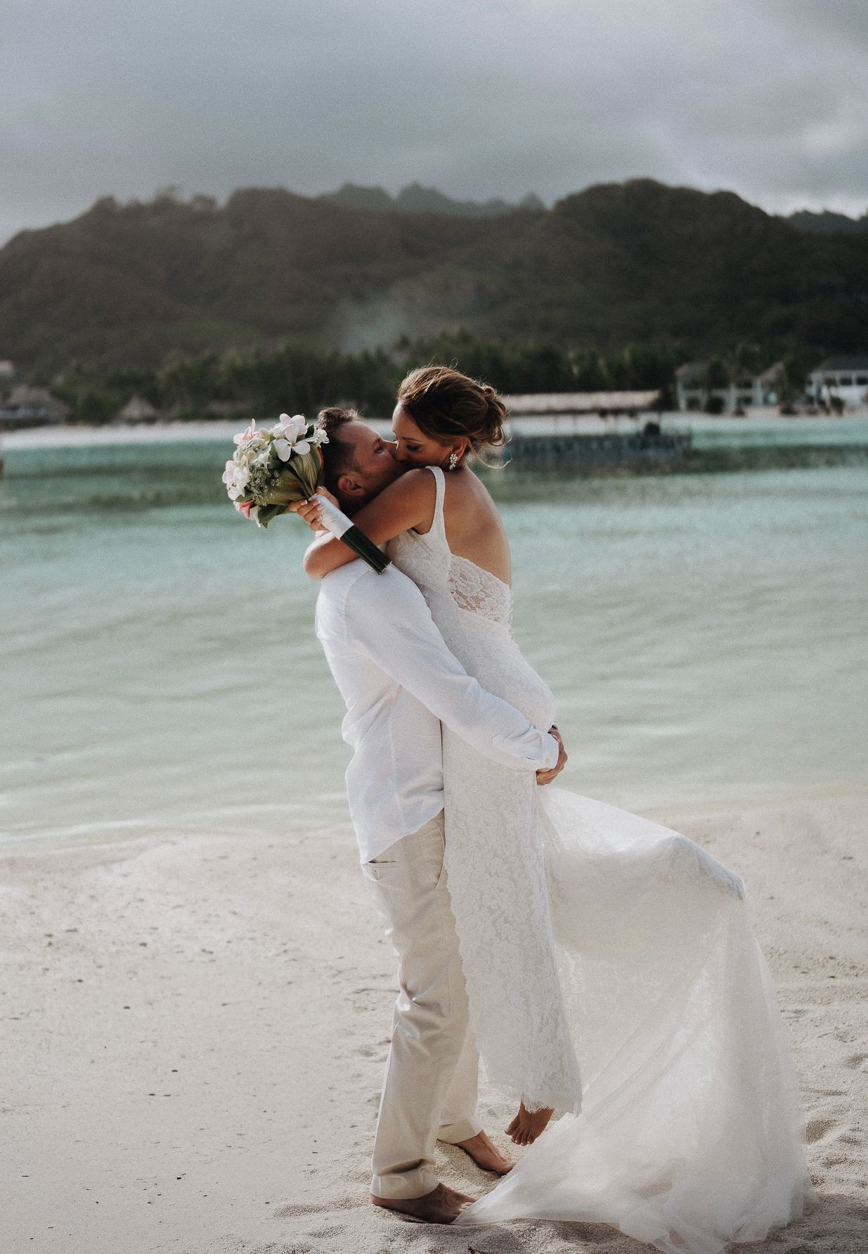A romantic beach wedding sequence showing a couple in white attire dancing and embracing on a tropical shoreline.