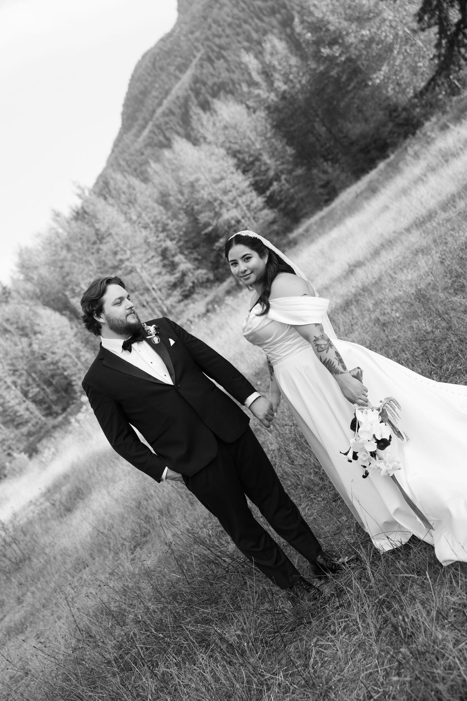 Artistic black and white wedding photo series showing couple lying in grass field creating romantic silhouettes.
