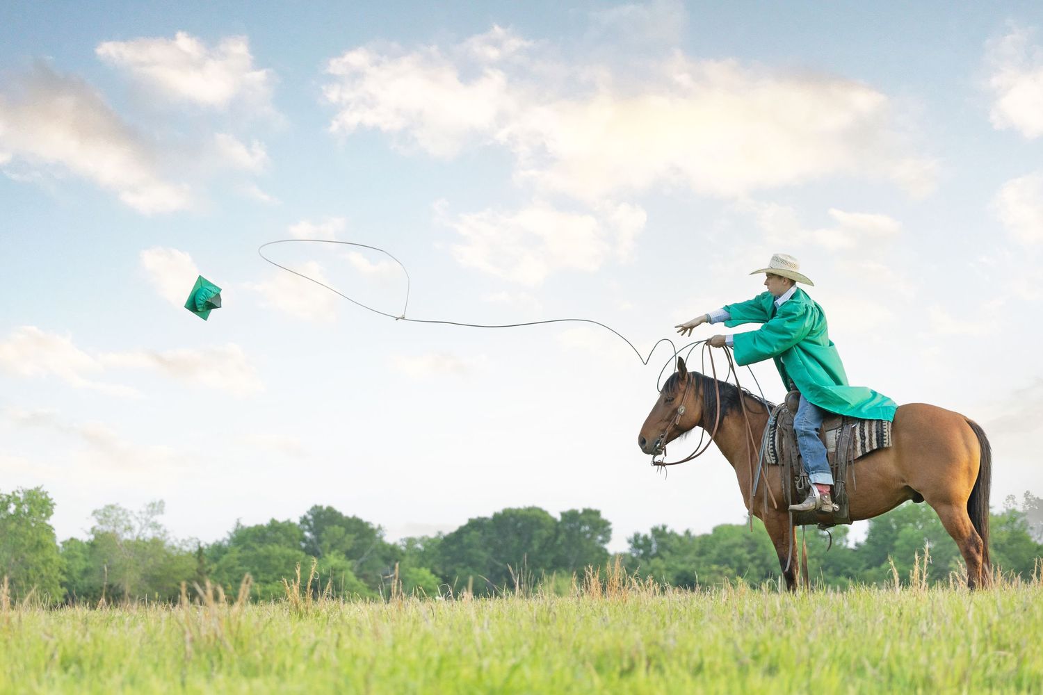young man sitting horseback wearing a graduation gown, throwing a lasso to catch a graduation cap. equestrian senior pictures